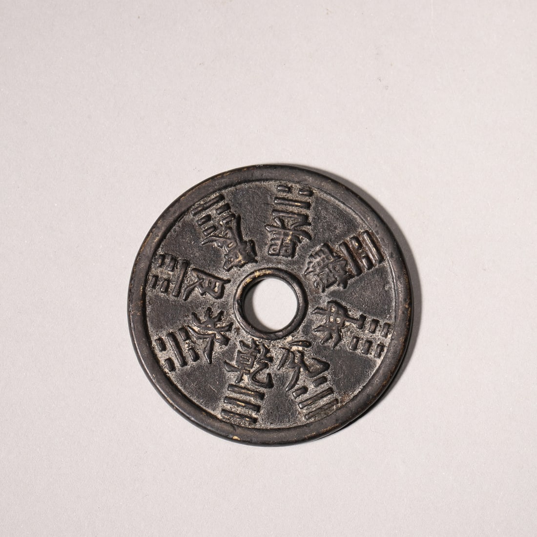 A Bronze Mountain Ghost and Eight Trigrams Charm Coin, Qing Dynasty: D 4.8cm (1.89 in); Wt 30.0g (0.07 lb)A Qing Dynasty bronze charm coin with a central hole. One side features the "Shan Gui Lei Ju" talisman inscription, while the other bears the Eight Trigrams. With 