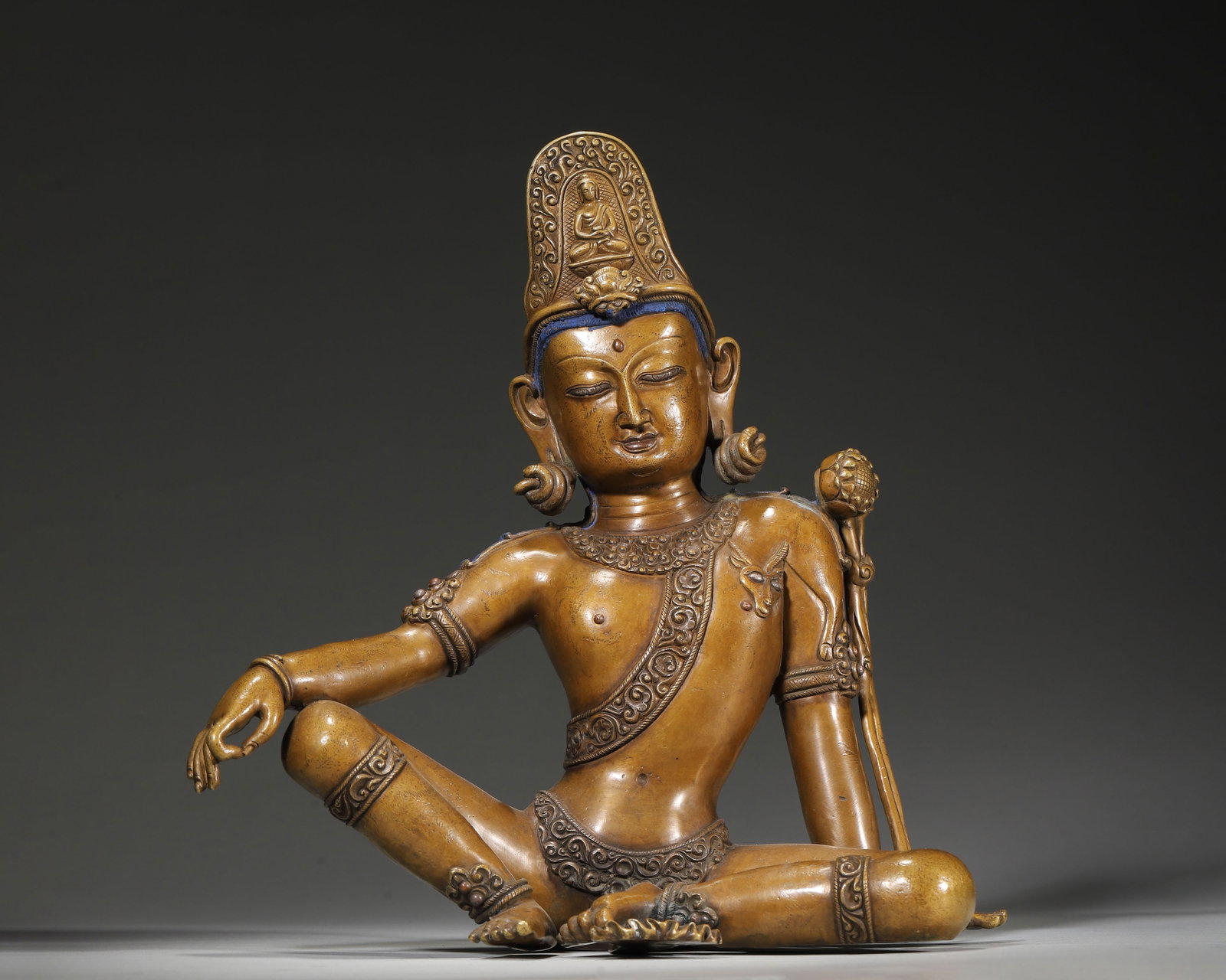 A COPPER ALLOY FIGURE OF AVALOKITESHVARA IN ROYAL EASE POSE WITH SILVER INLAY AND SEED SYLLABLES,: 9.45" x 3.94" x 9.84" (24cm x 10cm x 25cm) 6.37lb (2891g)This 14th–15th century Himalayan copper Avalokiteshvara, seated in royal ease pose, features serene features, blue hair, and inscribed seed s