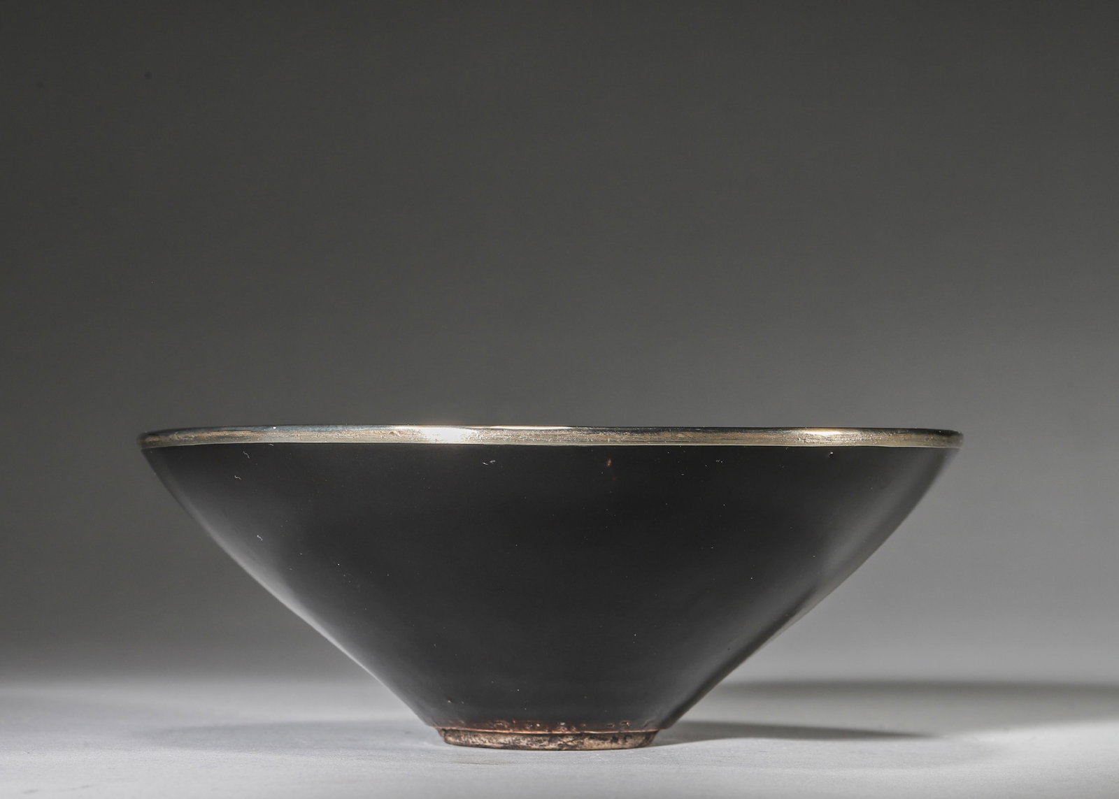 A SOUTHERN SONG DYNASTY JIZHOU KILN BLACK GLAZED LEAF PATTERN HAT-SHAPED TEA BOWL WITH SILVER RIM: Diameter: 15cm (5.91in) H: 6cm (2.36in)A fine Southern Song Dynasty Jizhou kiln black glazed tea bowl, iconic leaf (muye) motif, silver mounted rim, natural patina, exquisite craftsmanship, a top-tier