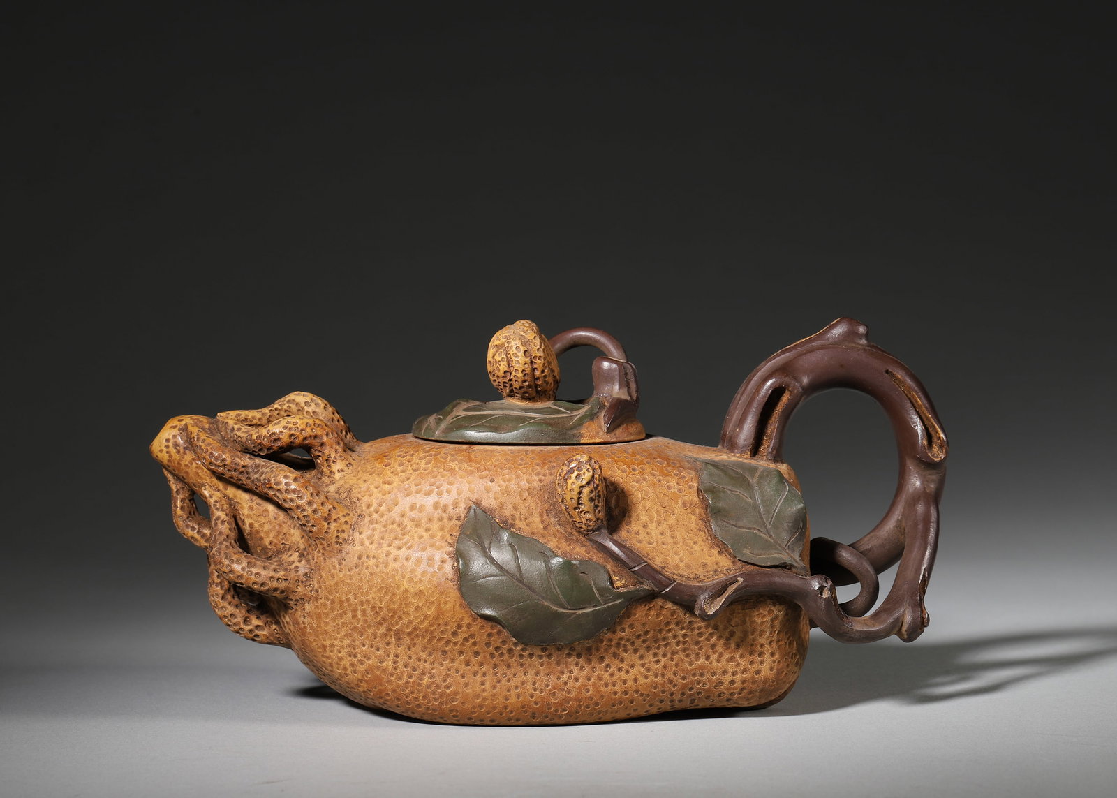 A FINE YIXING ZISHA BUDDHA'S HAND-FORM TEAPOT, ATTRIBUTED TO JIANG RONG: 7.87in x 3.94in x 3.94in (20.0cm x 10.0cm x 10.0cm)This exquisite teapot is masterfully crafted by renowned artist Jiang Rong, modeled after a Buddha's hand citron. Its realistic texture, vine-like ha