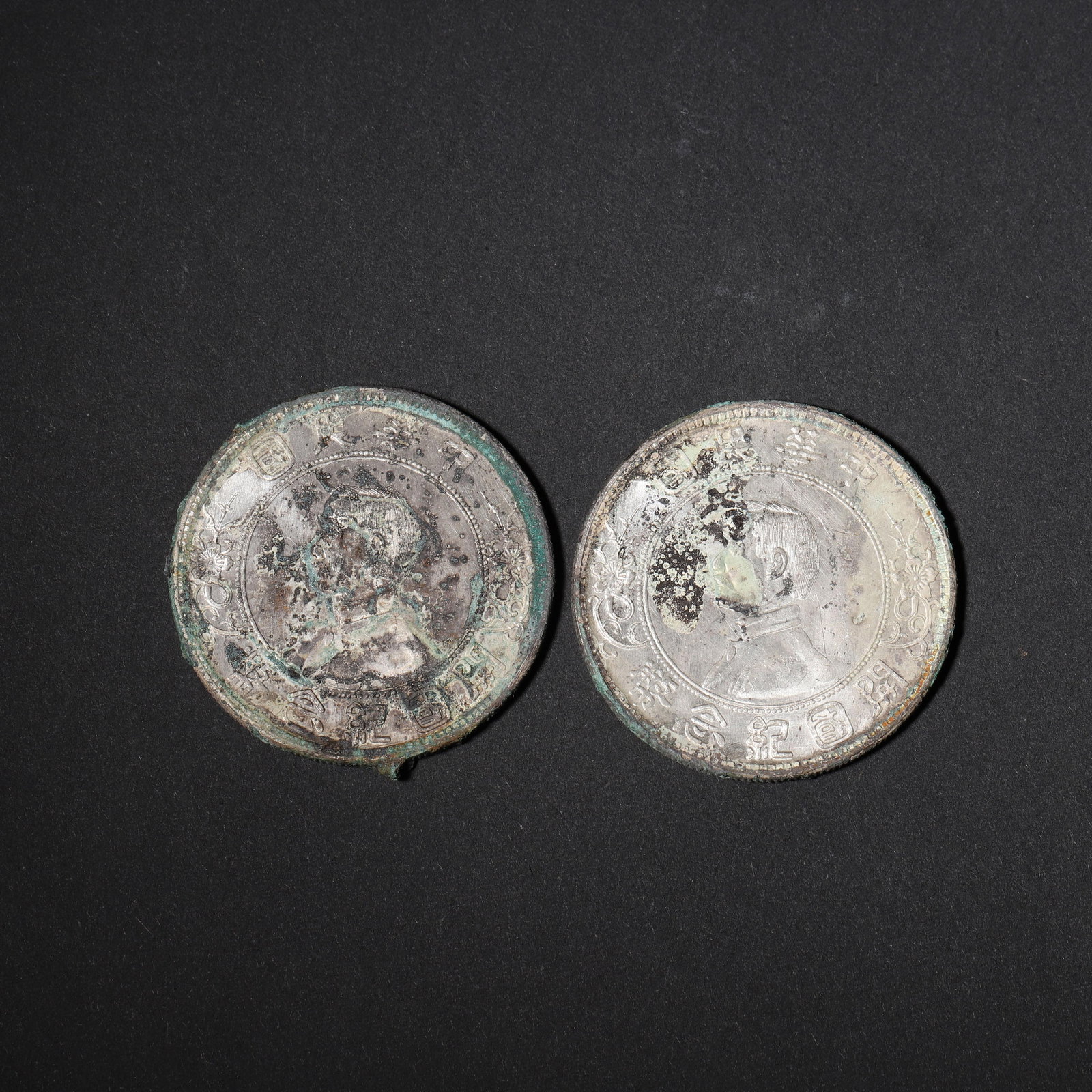 PAIR OF SUN YAT-SEN COMMEMORATIVE SILVER DOLLARS,Republic of China: 1.57in (4.0cm) 0.121lbs (55g)This pair of silver coins features an aged patina with green verdigris and soft silver luster. The obverse displays a profile portrait, while the reverse shows grain wreat