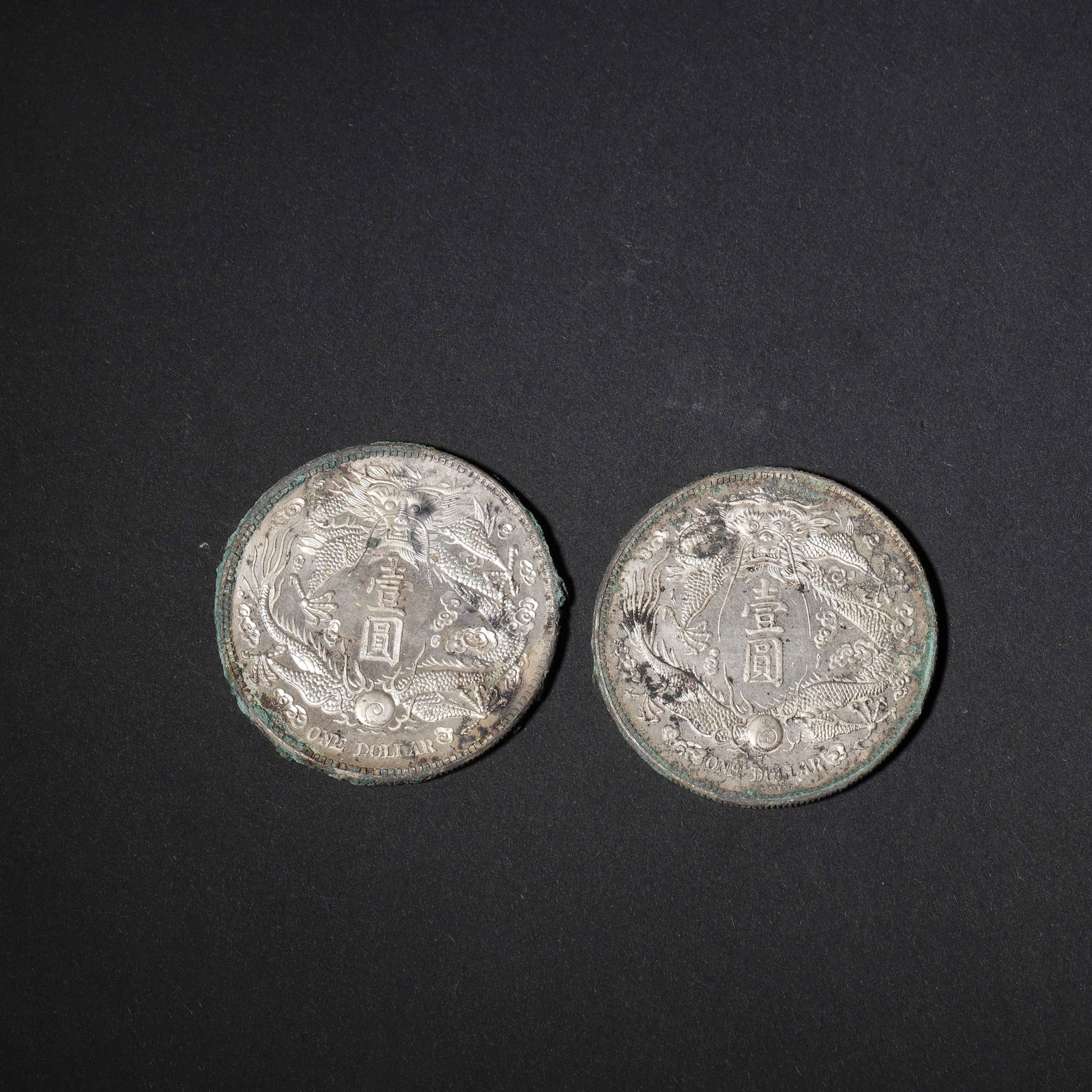 PAIR OF DA QING SILVER DOLLARS WITH LONG-BEARDED DRAGON,Qing Dynasty,China: 1.57in (4.0cm) 0.121lbs (55g)This pair of silver coins boasts a robust patina with green verdigris and silver luster. The obverse features inscriptions and floral motifs, while the reverse showcases a