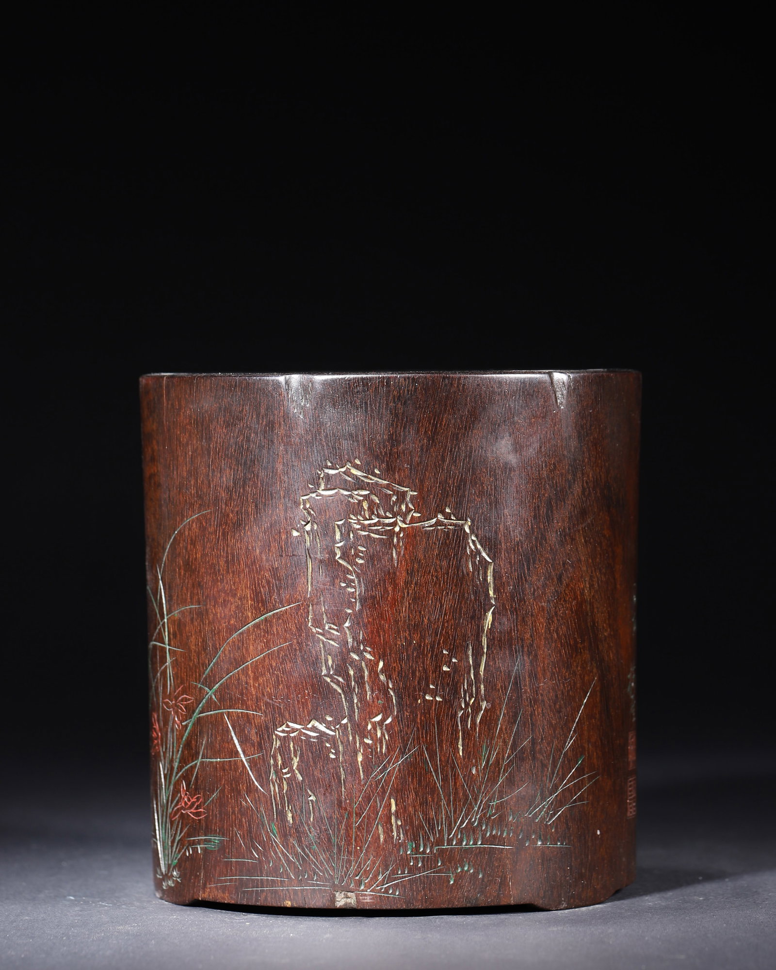 QING DYNASTY, A ZITAN BRUSH POT CARVED WITH ORCHID AND ROCK DESIGN, INSCRIBED "MEI SHENG": 5.91" x 6.3" (15.0cm x 16.0cm) 1.947lb (883g)This fine zitan brush pot is exquisitely carved with orchids and rockery in light relief, accented with red and green pigments. The reverse side bears a lo