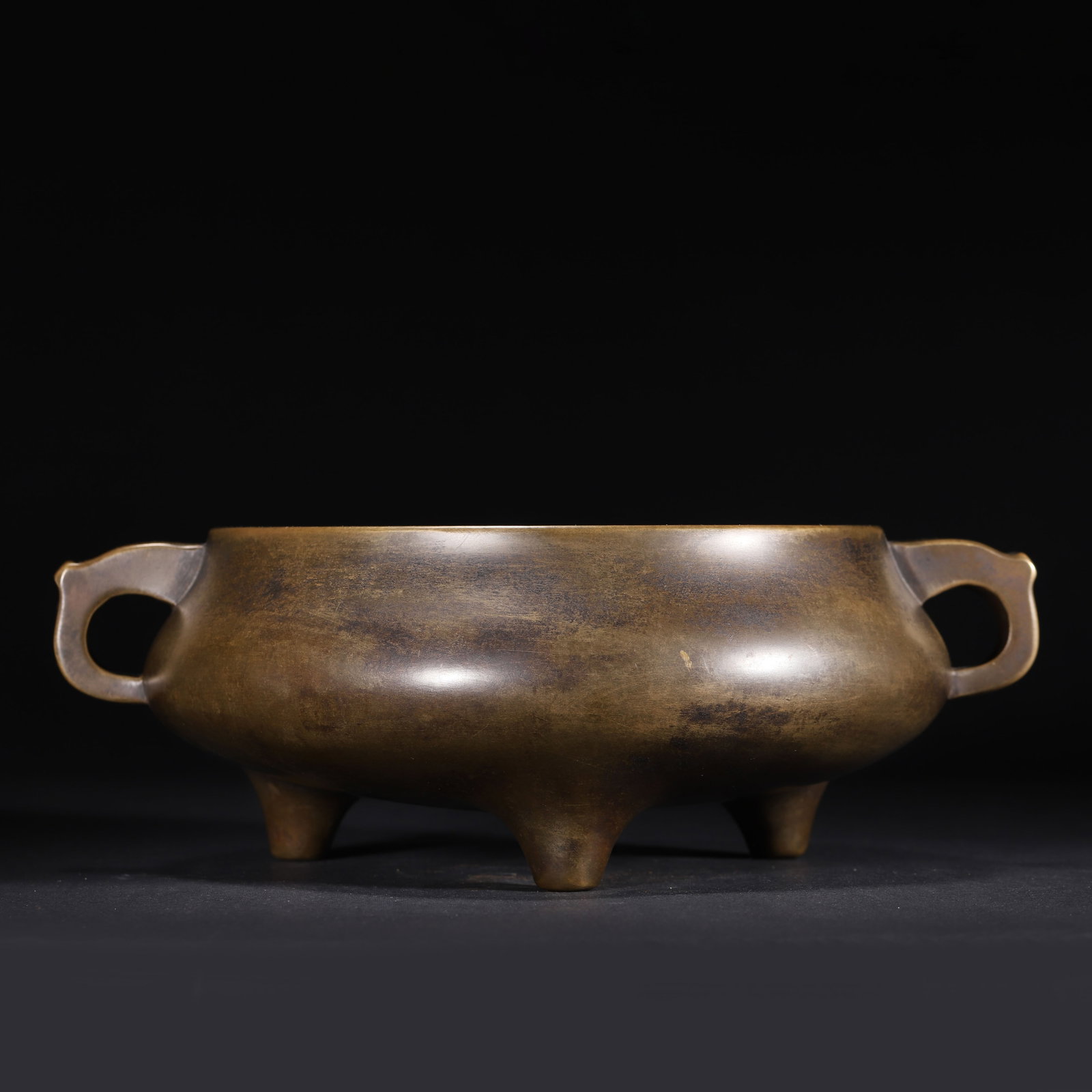 MING DYNASTY, XUANDE PERIOD, A FINE BRONZE TRIPOD CENSER WITH 'XUAN DE NIAN ZHI' MARK: 9.84" x 3.54" (25.0cm x 9.0cm) 6.929lb (3143g)This exceptional Xuande-period bronze censer, an imperial masterpiece, features a compressed body, elegant handles, and sturdy tripod feet. Its rich patin