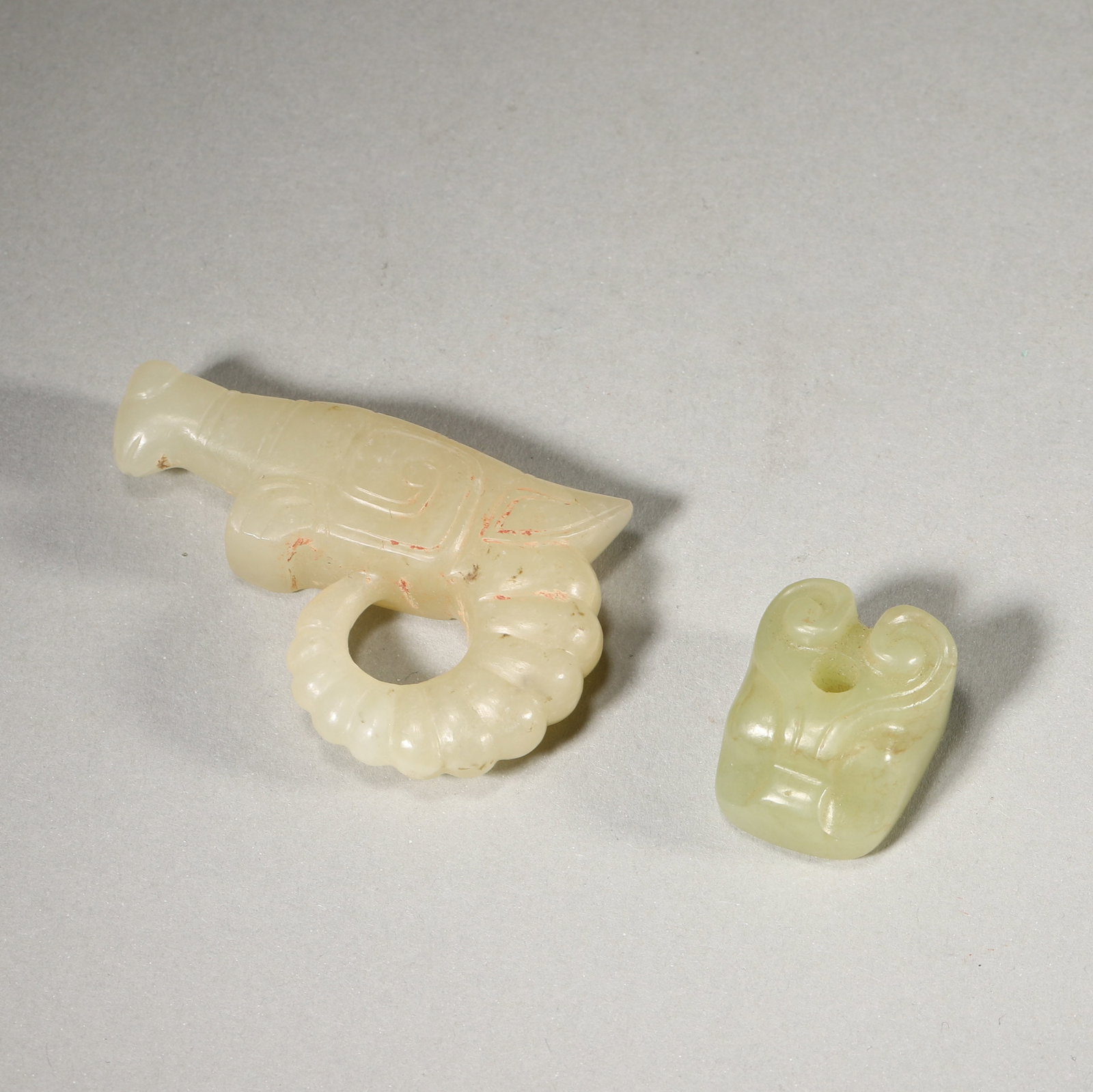 A SET OF TWO JADE BEAST PENDANTS, WESTERN ZHOU DYNASTY: L: 5.5cm (2.17in) W: 3.5cm (1.38in) Weight: 39g (0.09lb)A fine set of two Western Zhou jade beast pendants, archaic carving, cinnabar patina, creamy jade, exquisite craftsmanship, high historical and 