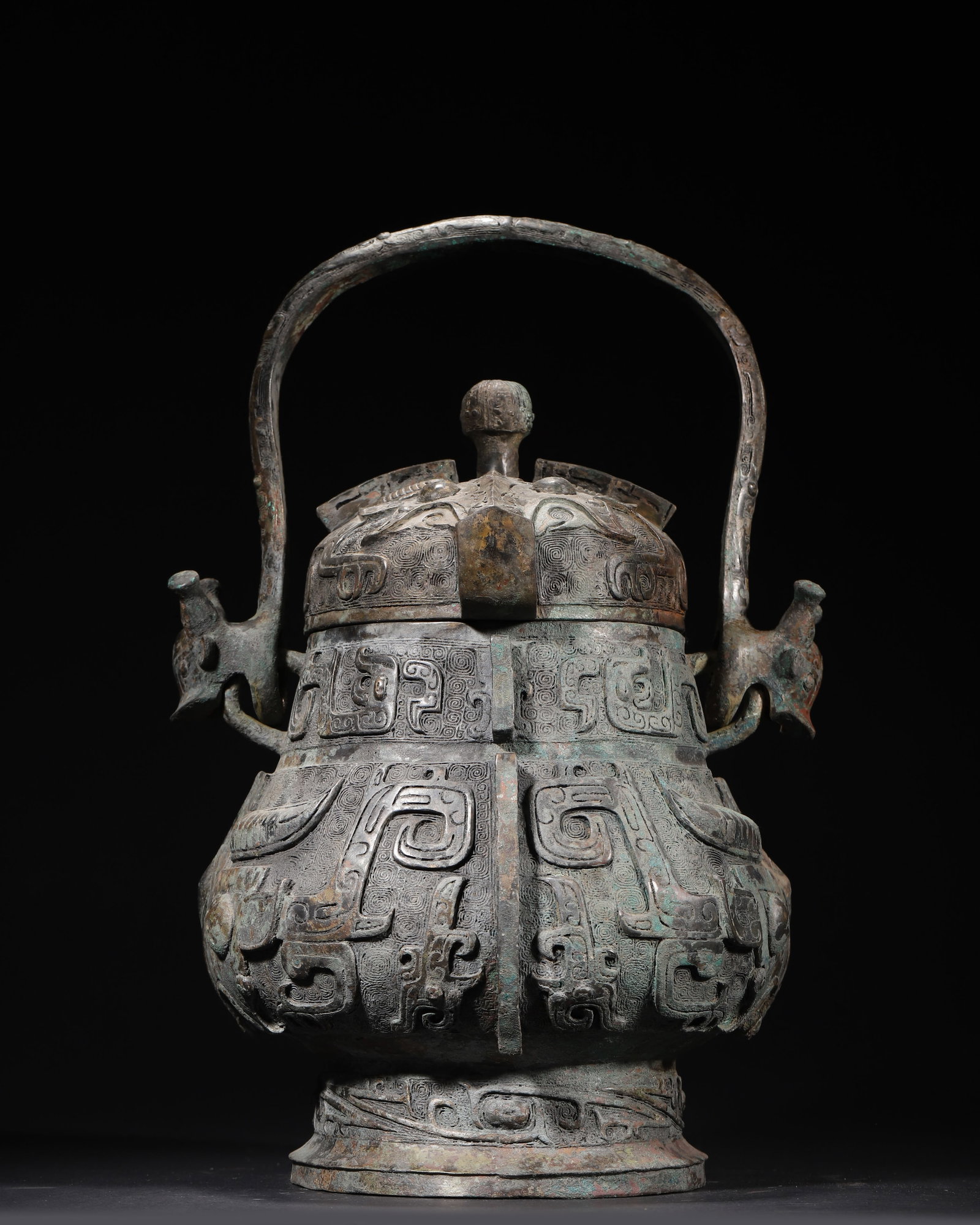 EARLY WESTERN ZHOU DYNASTY BRONZE YOU VESSEL WITH BEAST MASK PATTERN AND INSCRIPTIONS: 9.84in x 9.84in x 11.02in (25.0cm x 25.0cm x 28.0cm), 16.272lb (7381.0g)This Early Western Zhou bronze you vessel features a beast-head handle and high-relief beast mask patterns on a thunder-cloud gr