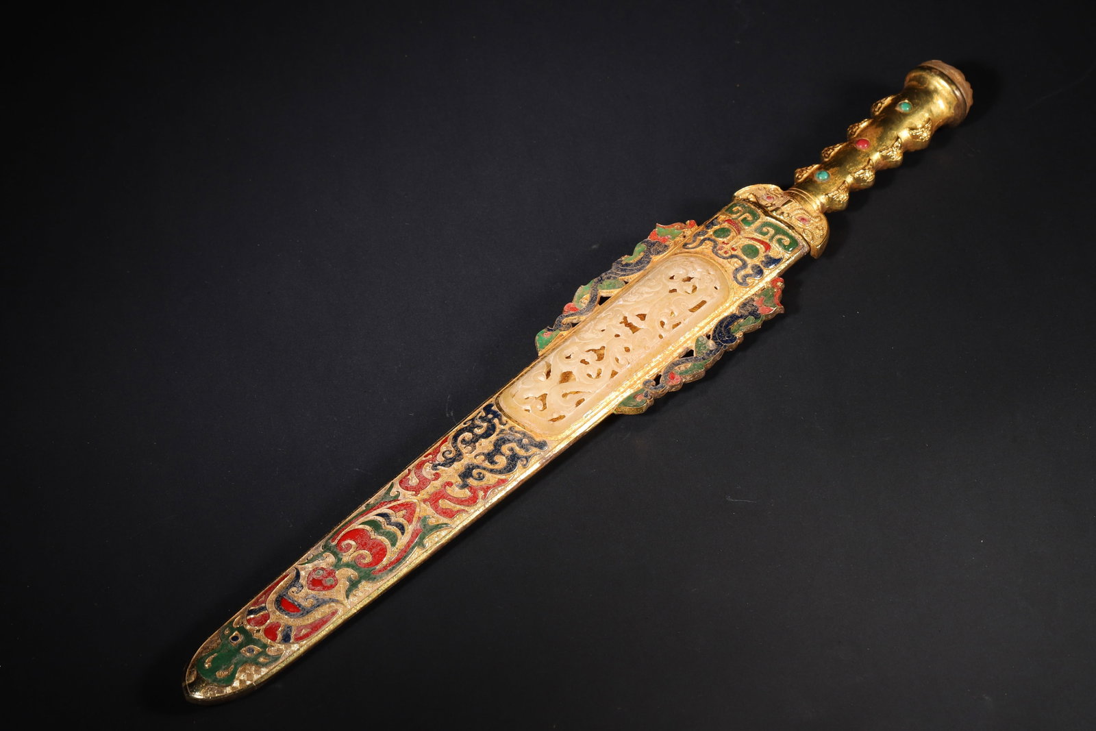 A FINE HAN DYNASTY GILT-BRONZE SHORT ORNAMENT WITH POLYCHROME DECORATION, INLAID JADE AND GEMSTONES: 25.98in x 3.54in (66.0cm x 9.0cm), 3.832lb (1738.0g)This Han Dynasty short ornament and scabbard are exquisitely gilt-bronze with polychrome decoration, inlaid with jade chi-dragon carvings and gemsto