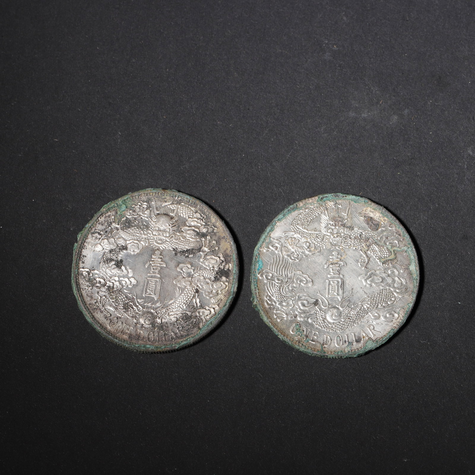 SET OF TWO DA QING SILVER ONE DOLLAR COINS,Qing Dynasty,China: 1.57in (4.0cm) 0.121lbs (55g)This set of two silver coins features a robust patina with green verdigris and soft silver luster. The obverse bears inscriptions and floral motifs, while the reverse show
