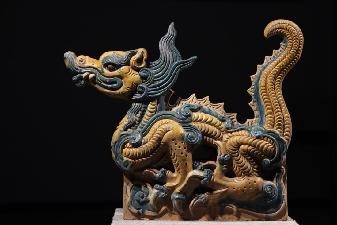 A LARGE SAN-CAI GLAZED POTTERY DRAGON ROOF ORNAMENT, MING DYNASTY, 14TH–17TH CENTURY: Length x Height: 31.50in x 26.38in (80.0cm x 67.0cm)Crafted in Shanxi, this Ming dragon ornament features a dynamic coiled body with vivid yellow and green glazes. Its intricate scales and cloud base 