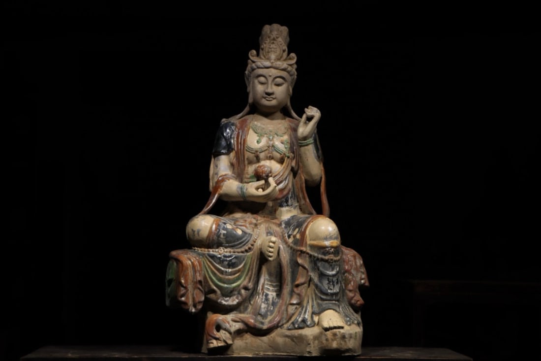 A SANCAI GLAZED POTTERY SEATED BODHISATTVA, TANG DYNASTY: Width x Height: 21.26in x 38.19in (54.0cm x 97.0cm)A magnificent sancai glazed pottery seated Bodhisattva, Tang Dynasty. With a serene, full-faced visage, elaborate adornments, and flowing robes, it e