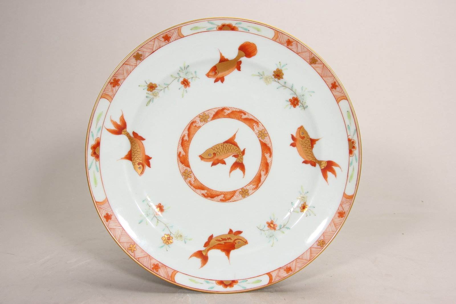 A FINE QING TONGZHI PERIOD CORAL-RED GILDED DISH WITH FISH AND ALGAE MOTIFS: D8.35in (D21.2cm)This imperial dish features five vividly painted gold-outlined koi fish in coral red, swimming among floral sprays. A rare Tongzhi mark example, embodying late Qing court porcelain cr