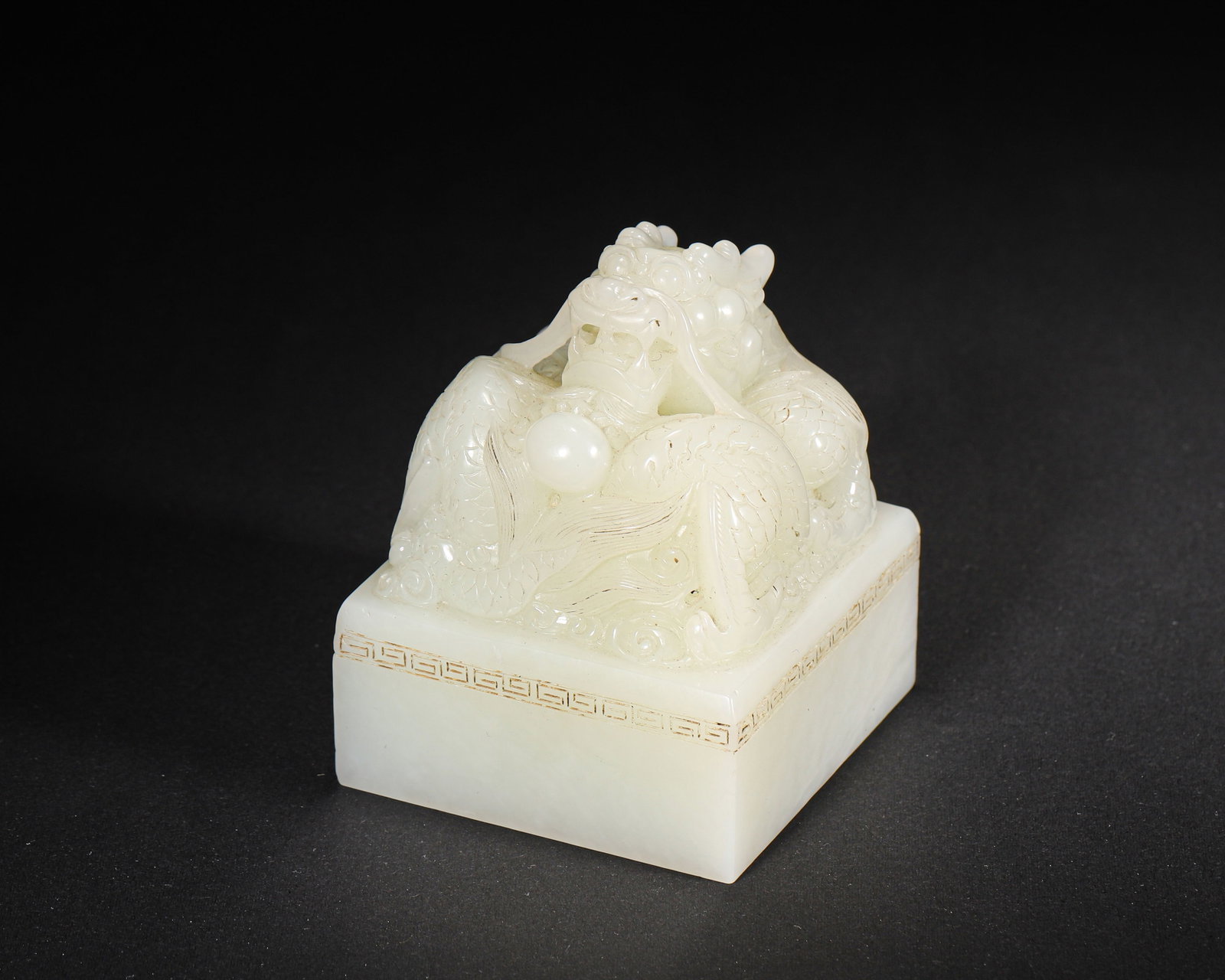A FINE IMPERIAL WHITE JADE 'DRAGON' SEAL, 'TIAN ZI XING BAO', MID-QING DYNASTY: 2.56in x 2.56in x 3.15in (6.5cm x 6.5cm x 8.0cm), 1.468lb (666.0g)This imperial seal, carved from fine white jade in the mid-Qing Dynasty, features a powerful coiled dragon finial. The seal face bears