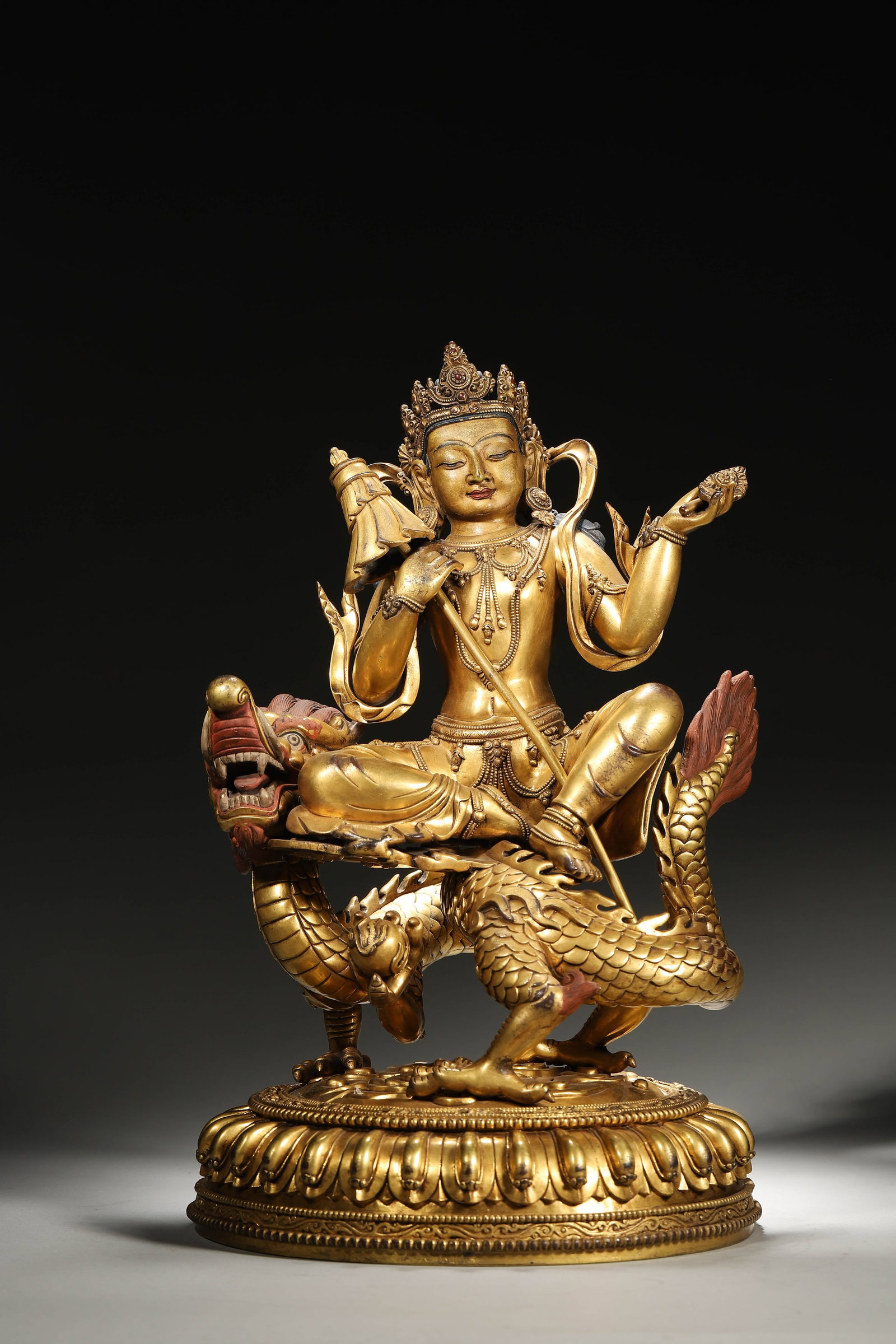 A GILT-BRONZE MANJUSHRI STATUE SEATED ON A DRAGON, QING DYNASTY: L: 21cm (8.27in) W: 23cm (9.06in) H: 37cm (14.57in) Weight: 9.59kg (21.14lb)This magnificent Qing Dynasty gilt-bronze Manjushri statue, seated on a lifelike dragon, features exquisite craftsmanship, r