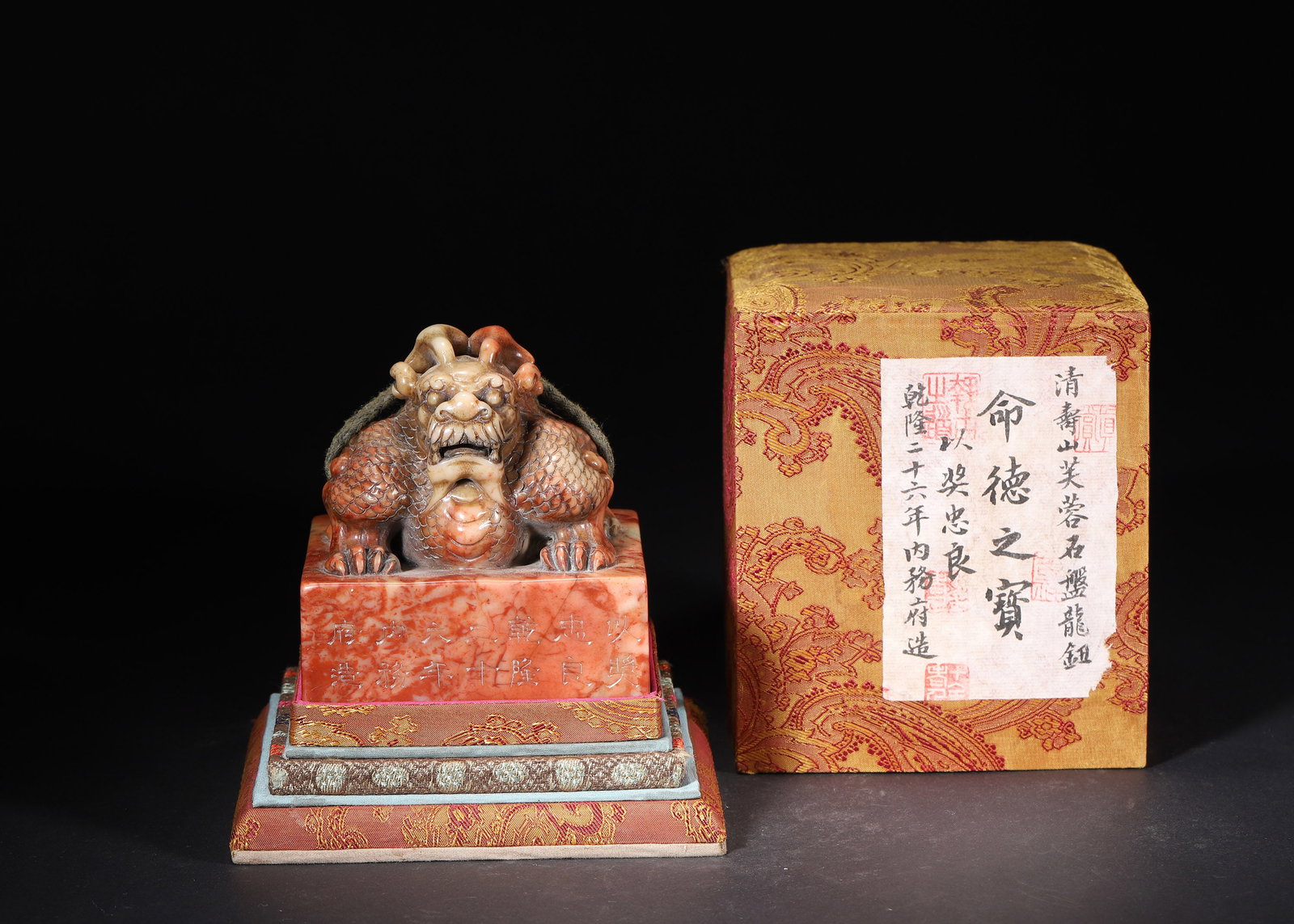 QIANLONG PERIOD, QING DYNASTY, A SHOUSHAN FURONG STONE SEAL 'MING DE ZHI BAO' WITH COILED DRAGON: 3.35" x 3.94" (8.5cm x 10.0cm) 2.421lb (1098g)Carved from Shoushan Furong stone, this imperial seal bears a coiled dragon knob and an inscription dated 1761. It retains its original brocade box, embod