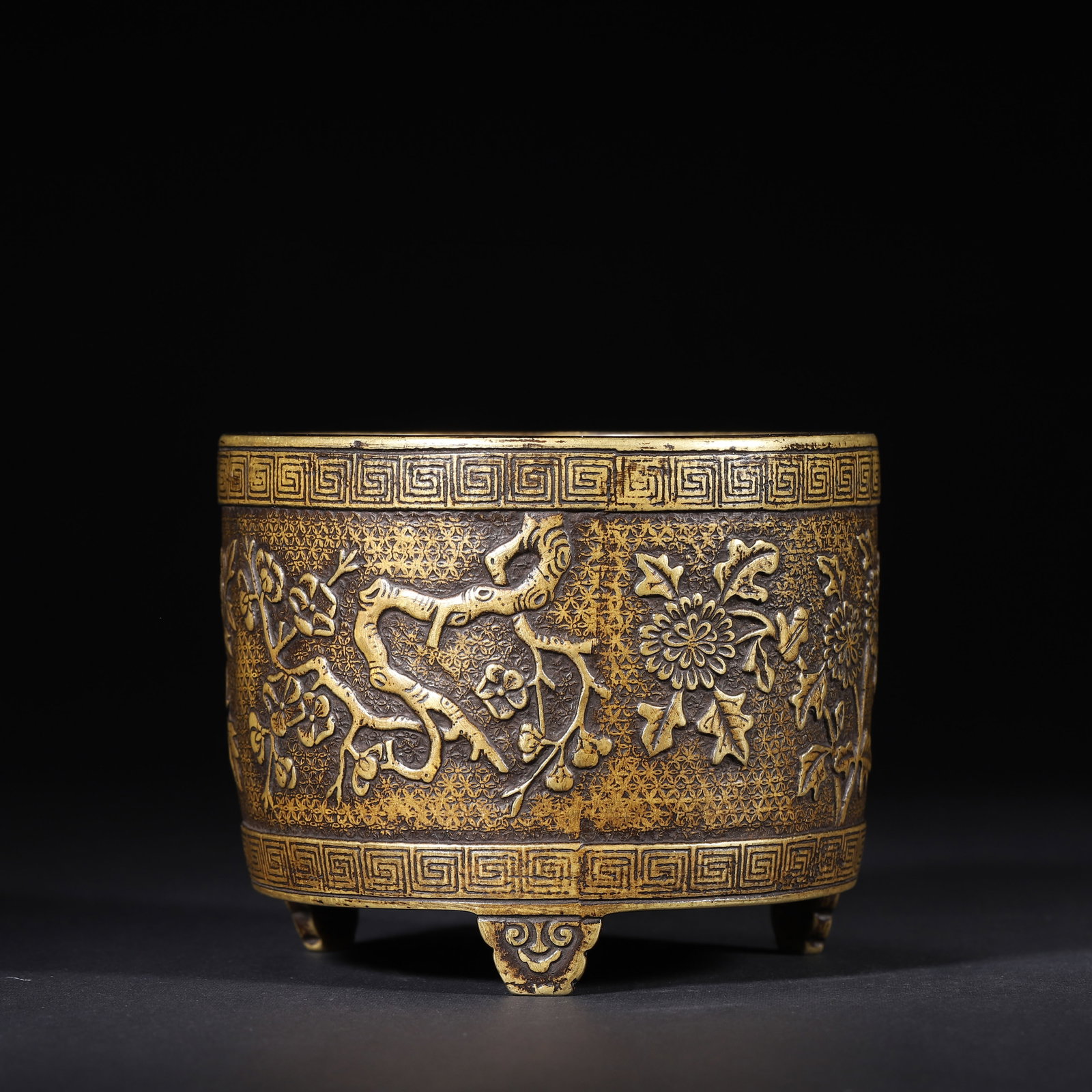 QING DYNASTY BRONZE TRIPOD CENSER WITH CARVED FOUR SEASONS FLORAL MOTIFS: 4.33" x 3.54" (11.0cm x 9.0cm) 2.93lb (1329g)This refined Qing Dynasty bronze tripod censer features intricate relief carvings of four seasons flowers on a brocade ground. Its robust form, cloud-shape