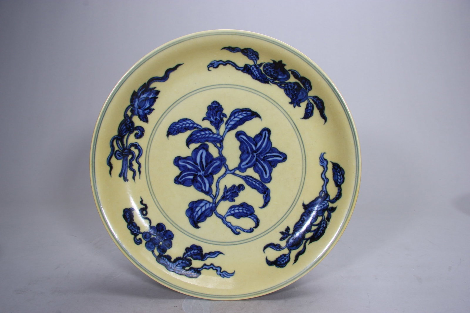 A FINE MING HONGZHI PERIOD YELLOW-GROUND BLUE AND WHITE FLORAL DISH: D10.51in (D26.7cm)This imperial dish features a rich imperial yellow glaze with vivid blue and white fruiting sprays, symbolizing prosperity. A rare Hongzhi example with Xuande mark, showcasing except