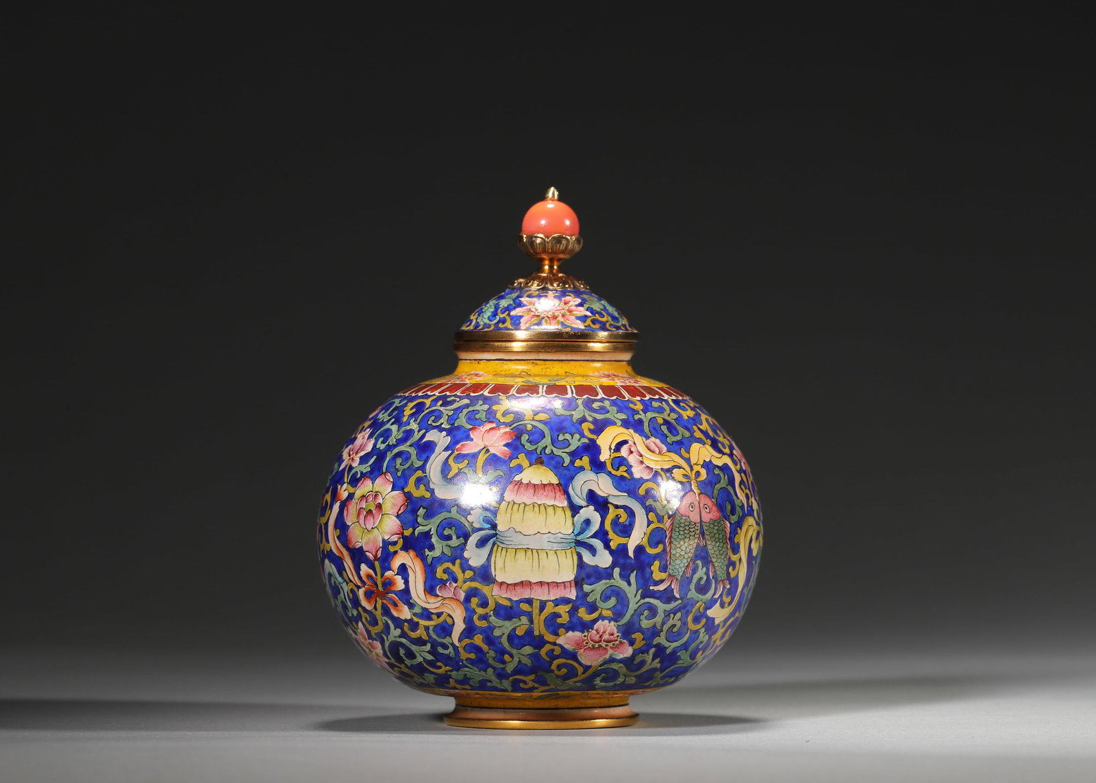 QIANLONG PERIOD, QING DYNASTY COPPER-BODIED ENAMEL LIDDED JAR WITH EIGHT AUSPICIOUS SYMBOLS: 3.15in (8.0cm), 0.633lb (287.0g)A fine Qianlong period copper enamel lidded jar with vibrant blue ground, eight Buddhist auspicious symbols, and coral finial. Marked "Qianlong Nian Zhi", it exemplifie