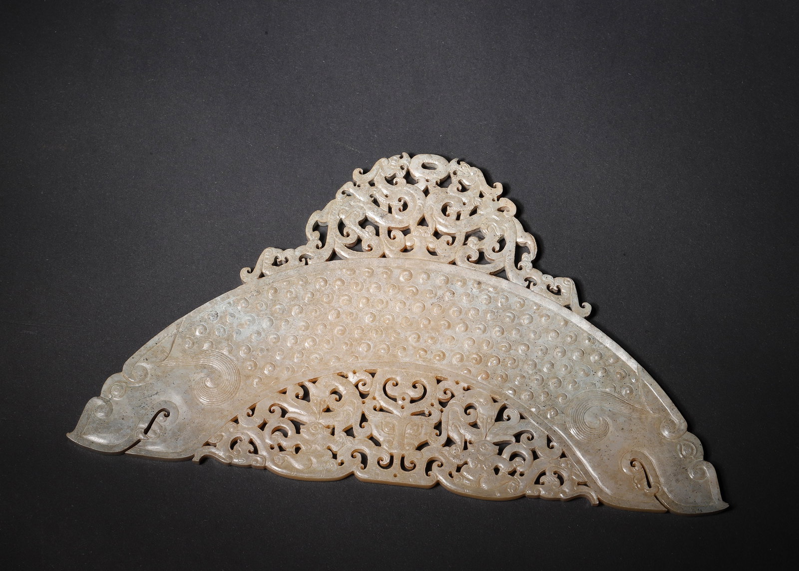 WESTERN HAN DYNASTY HETIAN JADE BI-SHAPED HUANG WITH OUTLINED DRAGON, PHOENIX AND BEAST MOTIFS: 8.27in x 4.33in (21.0cm x 11.0cm) 0.43lb (193.0g)A magnificent Western Han-era jade carving crafted from fine Hetian jade. Featuring a curved huang form adorned with raised grain patterns and exquisit