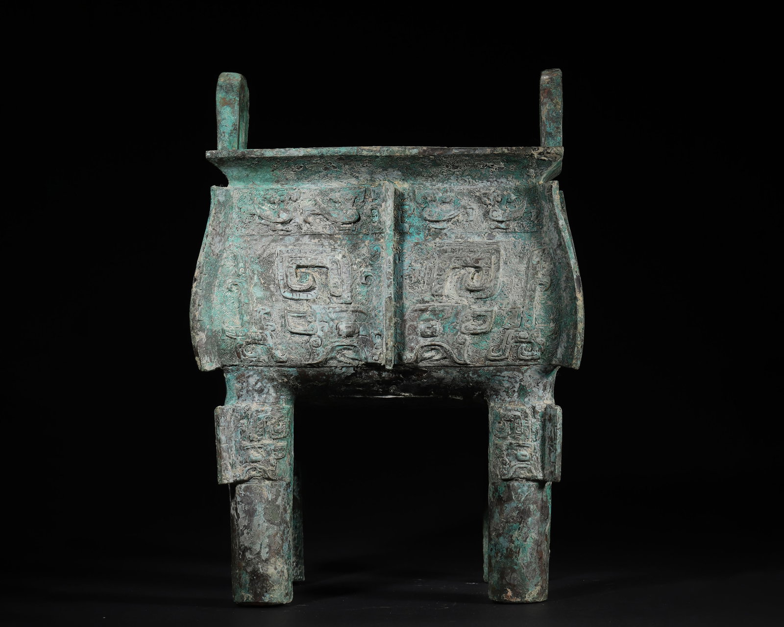 WESTERN ZHOU DYNASTY BRONZE SQUARE DING VESSEL WITH TAOTIE MASKS AND INSCRIPTIONS: 8.66in x 7.09in x 12.6in (22.0cm x 18.0cm x 32.0cm), 14.707lb (6671.0g)A fine Western Zhou bronze square ding vessel, with symmetric taotie masks, cloud-patterned ground, four pillar legs, and inscrip