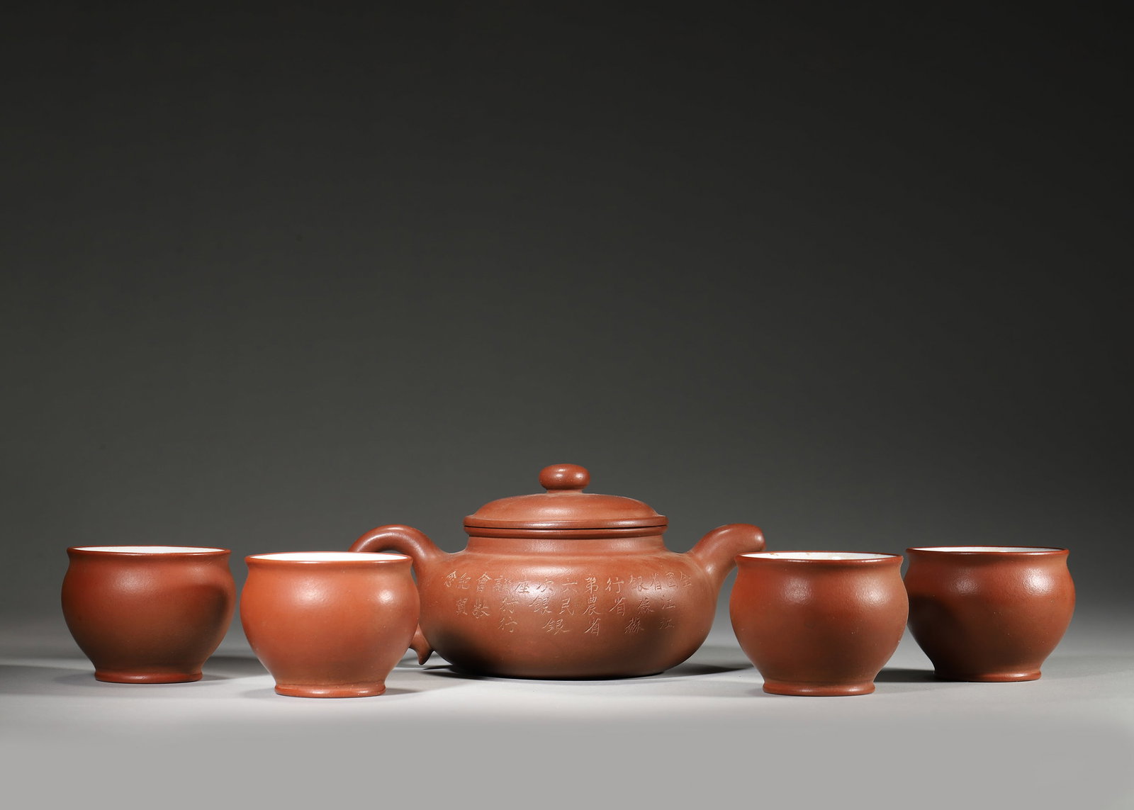 1946 (REPUBLIC PERIOD), A SET OF FIVE ZISHA GU GU TEAPOT AND CUPS "ZUO YOU LAN YAN" BY GU JINGZHOU: 7.09in x 5.12in x 3.54in (18.0cm x 13.0cm x 9.0cm)This 1946 set of five zisha wares by Gu Jingzhou includes a Gu Gu teapot and four cups. Made of fine bottom trough clear clay, the teapot is inscribed