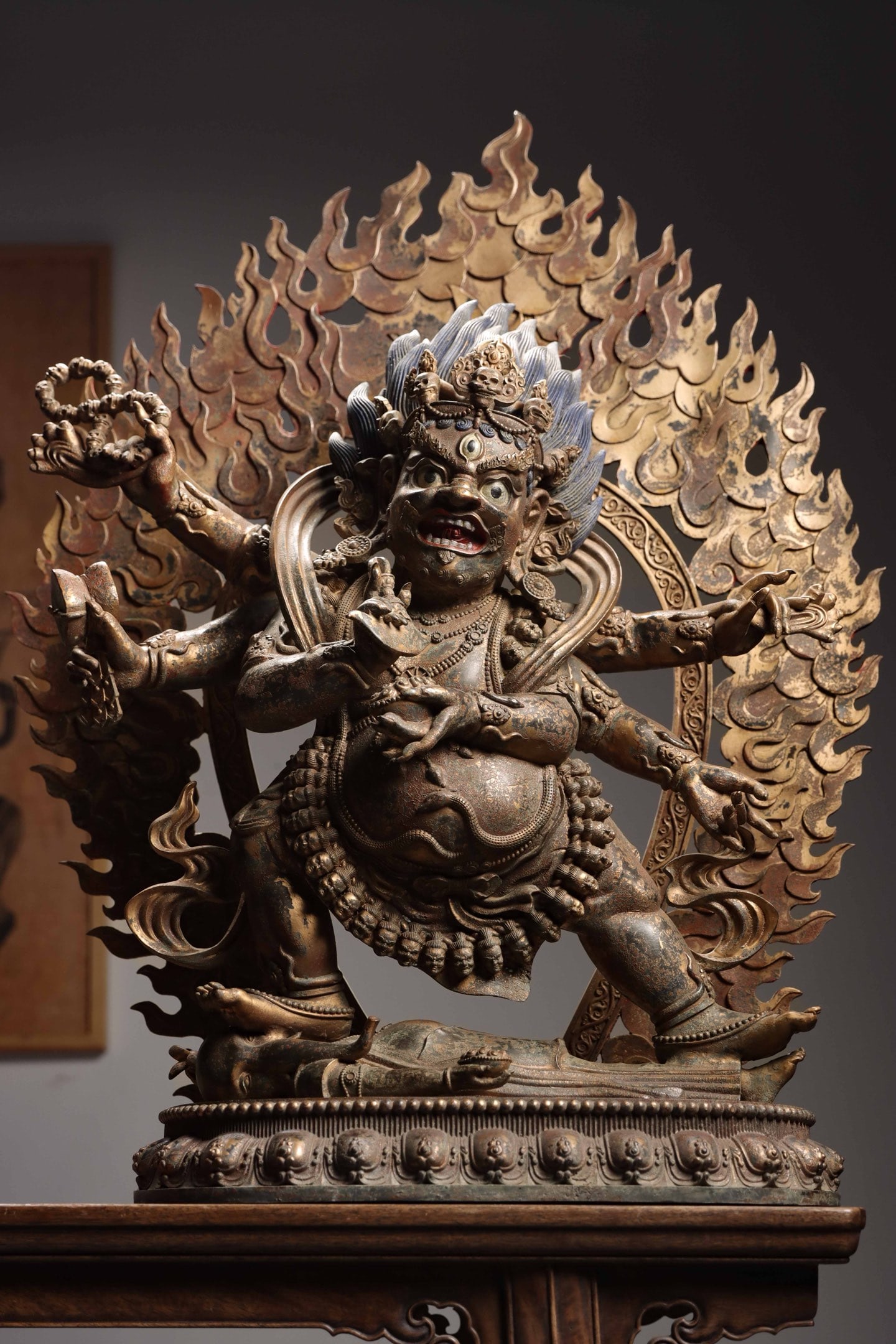 A GILT-BRONZE SIX-ARMED MAHAKALA STATUE, QING DYNASTY, TIBETAN STYLE: 31.1" x 23.62" x 11.42" (79cm x 60cm x 29cm) 66.36lb (30100g)A Qing Dynasty (1644-1912) Tibetan-style gilt-bronze Six-Armed Mahakala. Fierce expression, skull crown, six arms with ritual implements, f