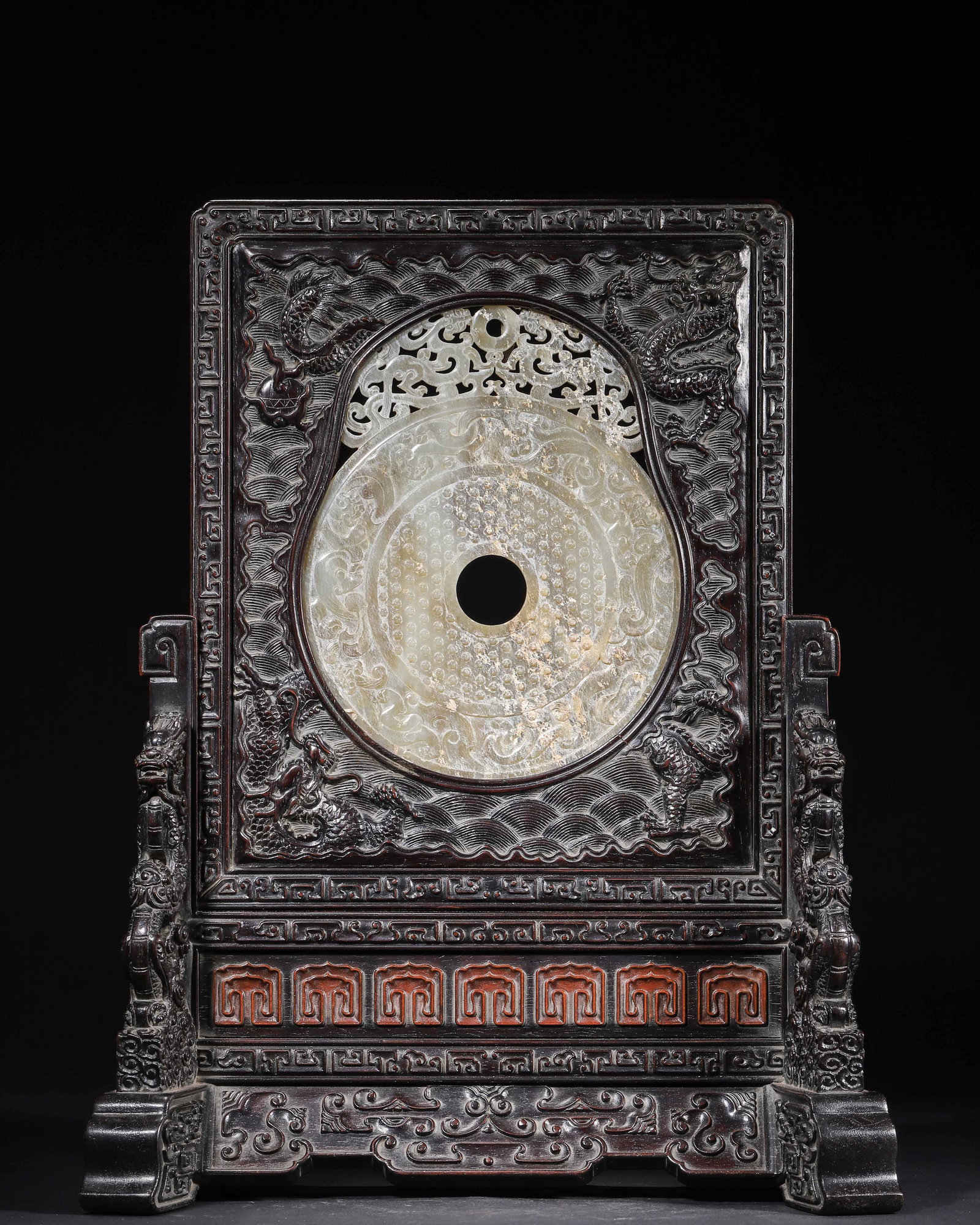 QING DYNASTY, A ZITAN TABLE SCREEN INSET WITH ARCHAISTIC JADE BI, CARVED WITH DRAGON AND CLOUD: 11.81" x 5.91" x 15.35" (30.0cm x 15.0cm x 39.0cm) 4.612lb (2092g)This table screen features a zitan frame carved with dynamic dragons and waves, inset with an archaistic celadon jade bi adorned with 