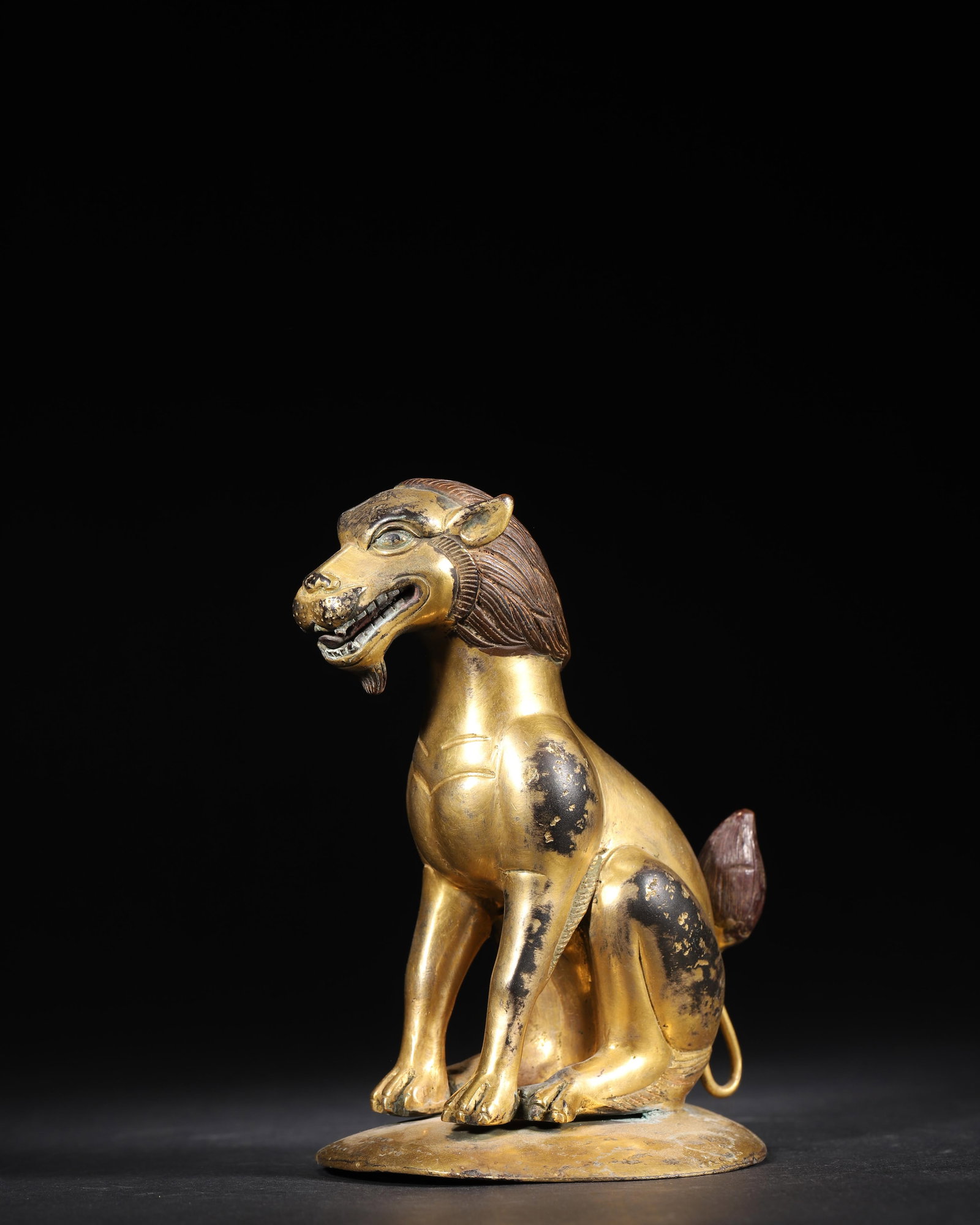 MING DYNASTY GILT-BRONZE SEATED AUSPICIOUS BEAST STATUE: 4.72 x 3.94 x 5.91 in (12 x 10 x 15 cm), 1.68 lbs (762 g)A fine Ming Dynasty gilt-bronze seated auspicious beast, with copper-inlaid mane and tail. The robust, dynamic form and well-preserved gilding 