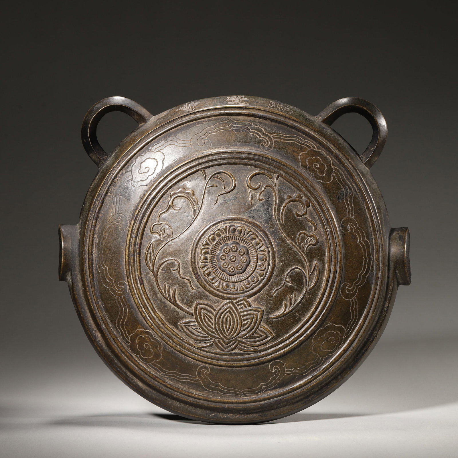 A CHINESE BRONZE BUDDHIST BELL WITH LOTUS PATTERN, QING DYNASTY: 10.63in x 3.54in x 10.24in (27.0cm x 9.0cm x 26.0cm) 8.32lb (3772.0g)A fine bronze Buddhist bell from the Qing Dynasty. Its flattened, robust body features a symmetrical double-loop handle, elaboratel