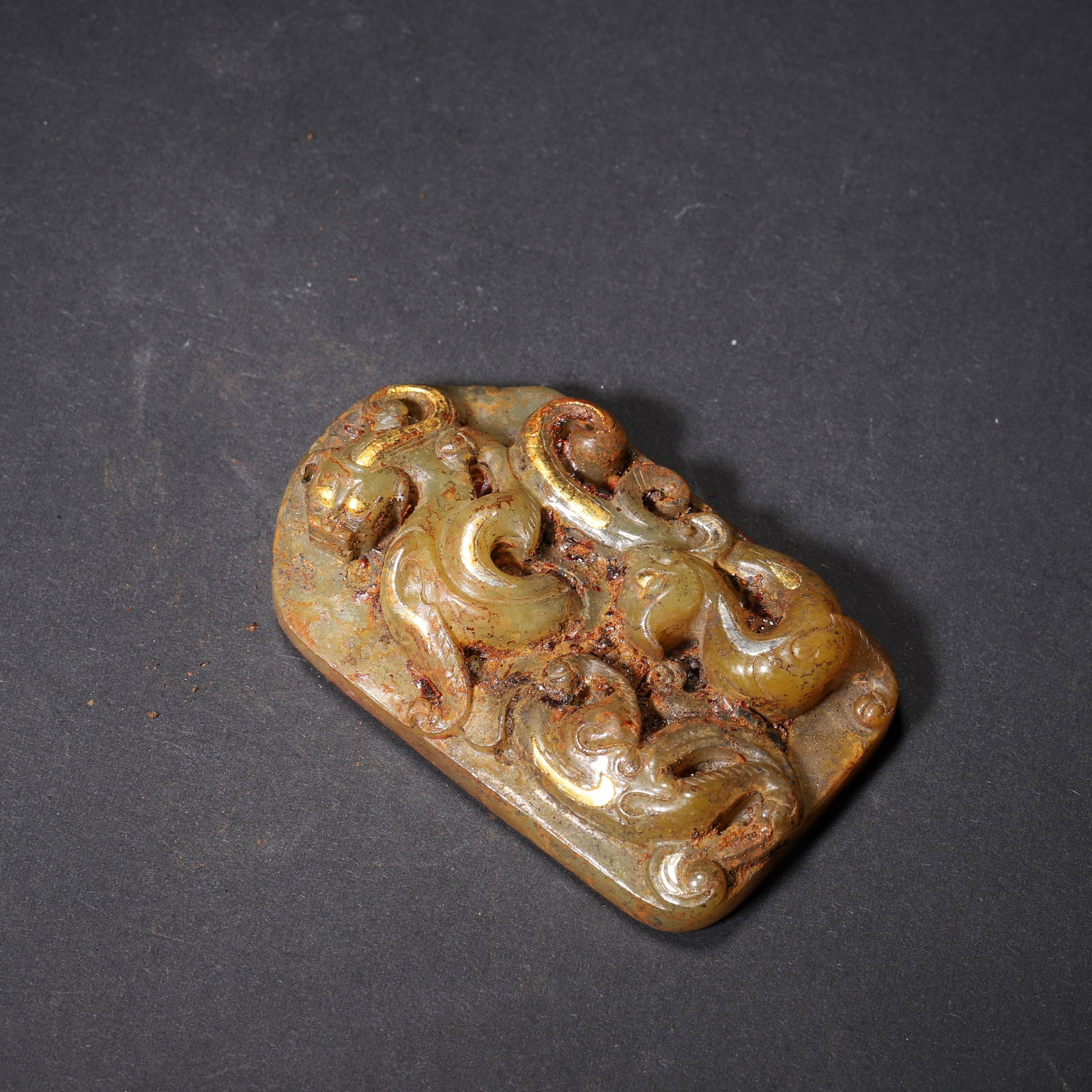 HAN DYNASTY GOLD-INLAID JADE DOUBLE-CHI DRAGON BELT PLAQUE: 2.64" x 1.57" (6.7cm x 4.0cm) 0.174lb (79g)Carved from Hetian green jade, this Han Dynasty belt plaque features high-relief intertwined Chi dragons with gold inlay. Its reverse is fully decorated with