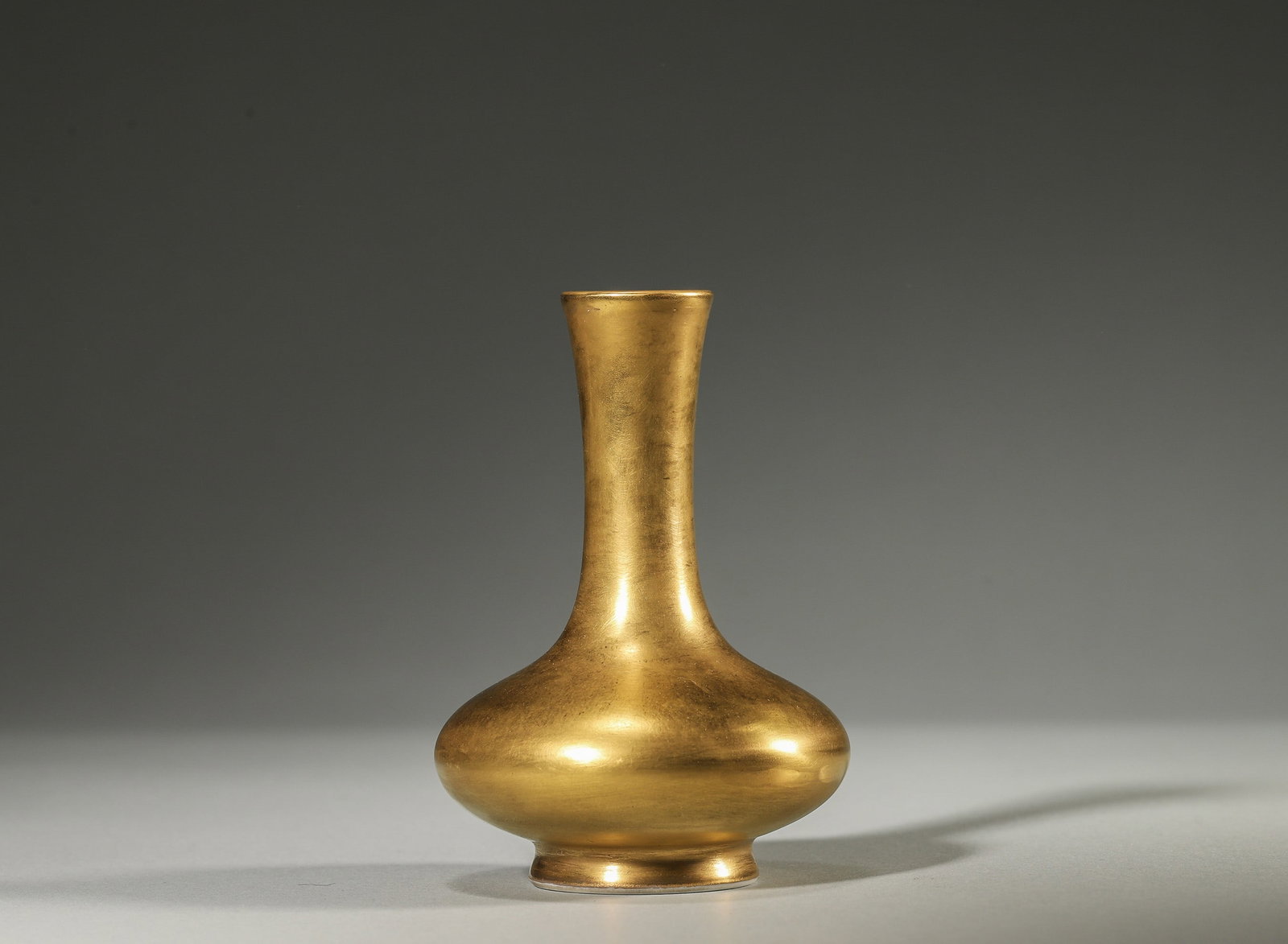 A FINE GILT-GLAZED LONG-NECK VASE, YONGZHENG MARK AND PERIOD, QING DYNASTY: Diameter: 7cm (2.76in) H: 10cm (3.94in)A superb Yongzheng period gilt-glazed vase, covered in rich golden glaze, elegant shape, standard imperial mark, extremely rare, high collection value.