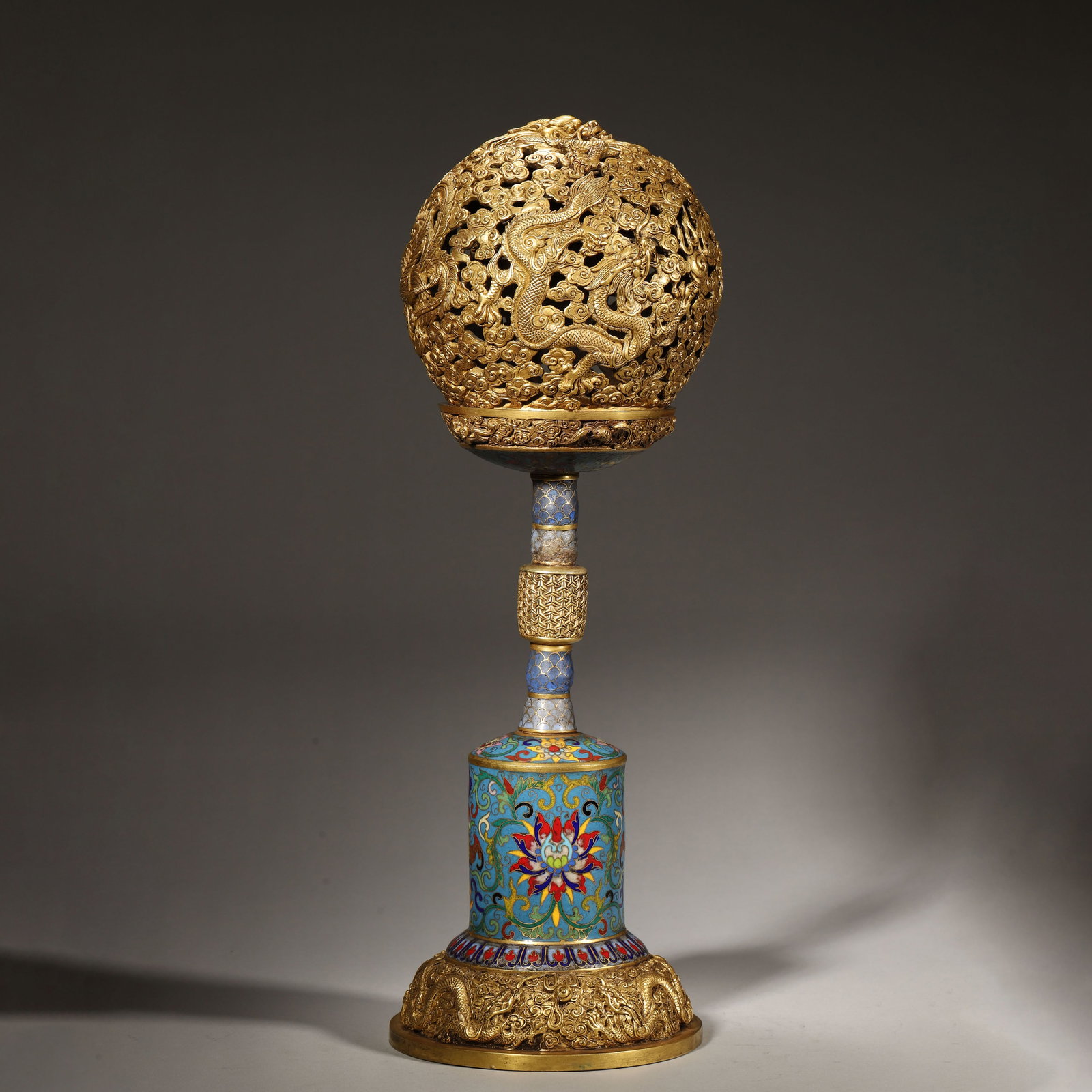 A RARE GILT-BRONZE AND CLOISONNÉ ENAMEL HAT STAND, QIANLONG PERIOD, QING DYNASTY: Diameter: 14cm (5.51in) H: 40cm (15.75in) Weight: 6139g (13.53lb)This rare Qianlong-period gilt-bronze and cloisonné enamel hat stand features exquisite openwork dragon-phoenix carvings. A supreme im