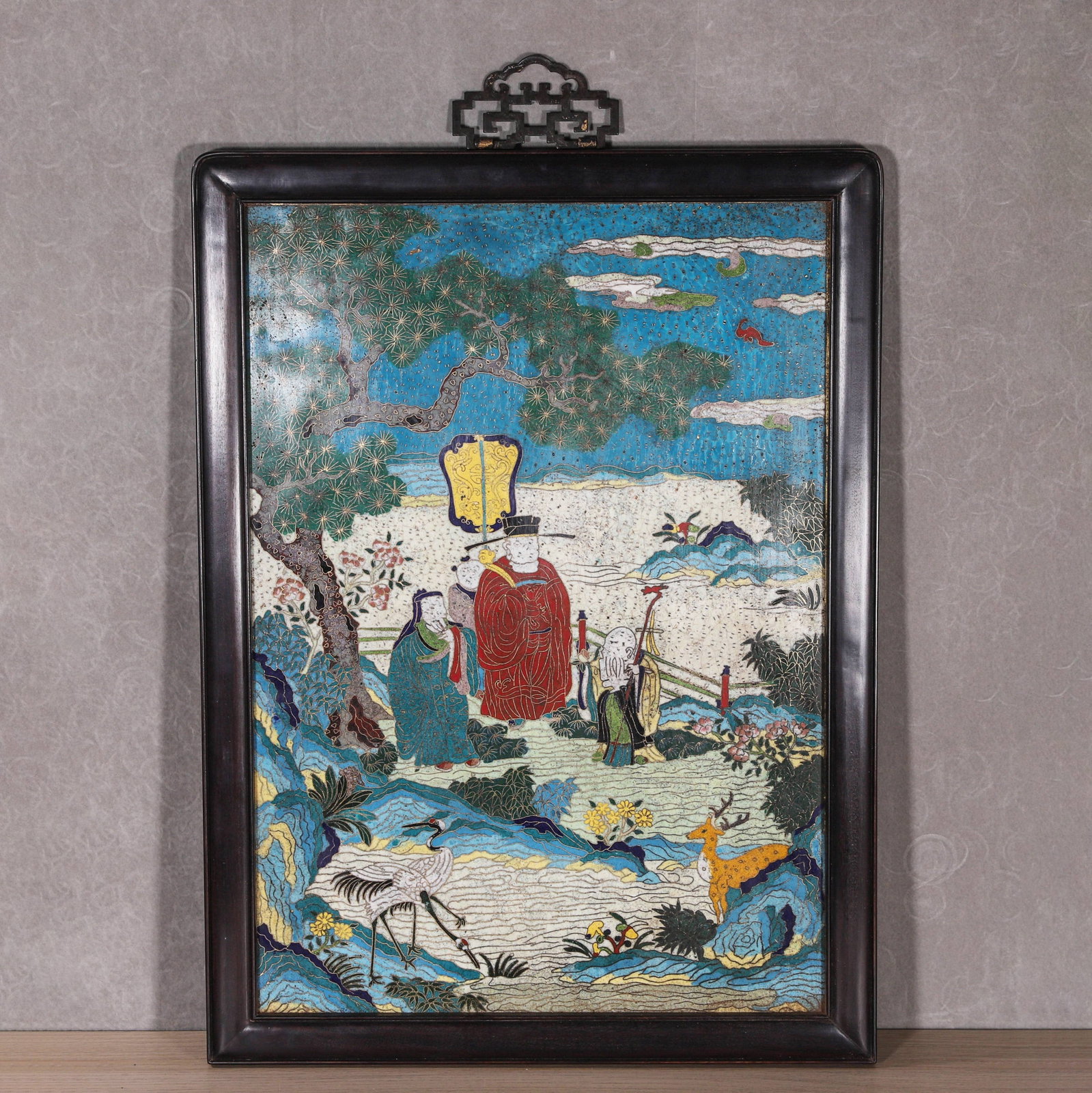 MID-QING DYNASTY GILT-BODY CLOISONNÉ ENAMEL HANGING SCREEN WITH "FU LU SHOU" IMMORTALS MOTIF: L: 46.5cm (18.31in) W: 33cm (12.99in)A mid-Qing Dynasty cloisonné enamel hanging screen with a gilt-copper body, featuring the "Fu Lu Shou" immortals. Intricate cloisonné work showcases cranes, deer