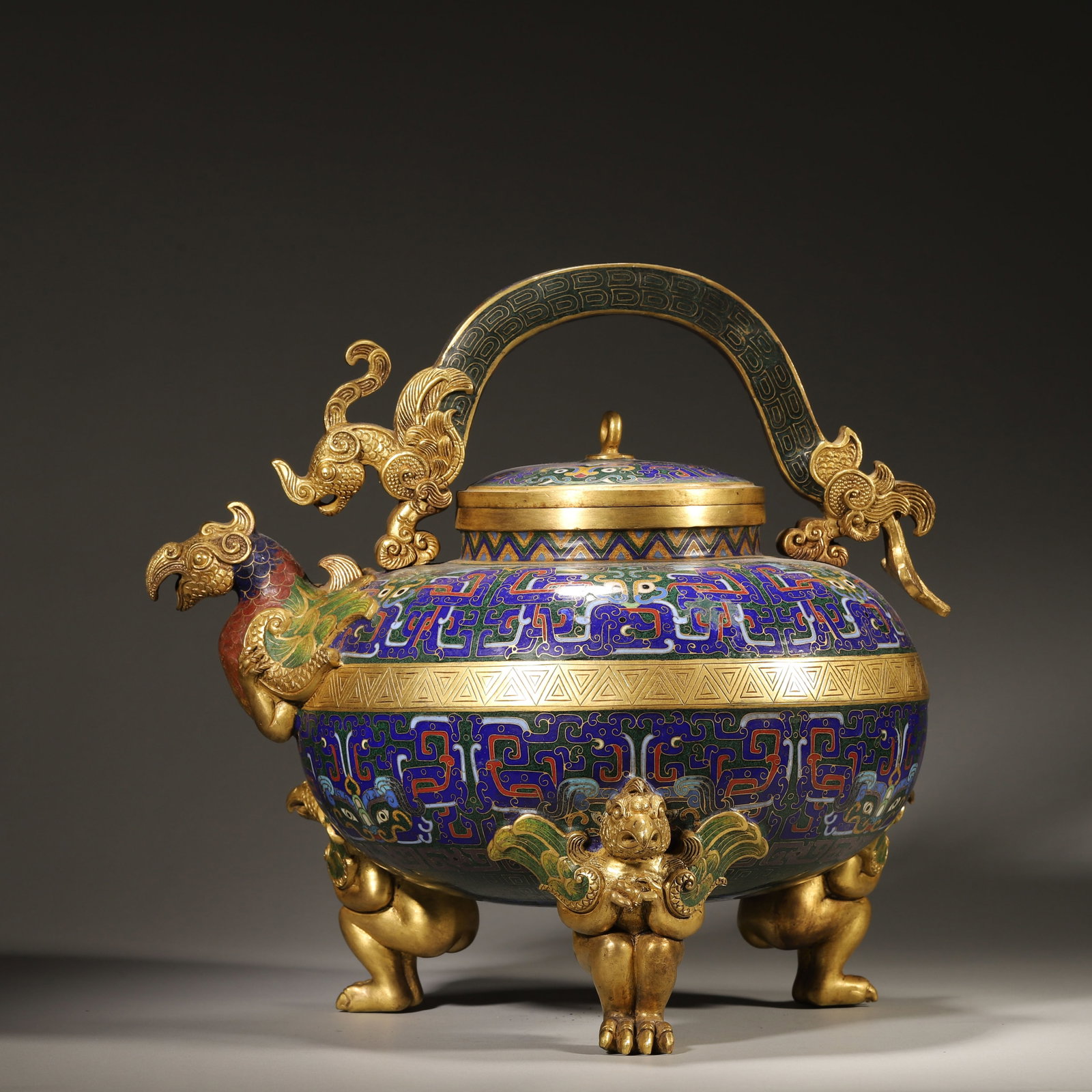 A MAGNIFICENT GILT-BRONZE AND CLOISONNÉ ENAMEL PHOENIX-HEAD LIFTED LIANG YOU, QIANLONG PERIOD, QING: L: 32cm (12.60in) W: 27cm (10.63in) H: 27cm (10.63in) Weight: 7072g (15.59lb)This magnificent Qianlong-period gilt-bronze and cloisonné enamel phoenix-head you is a supreme imperial masterpiece. With