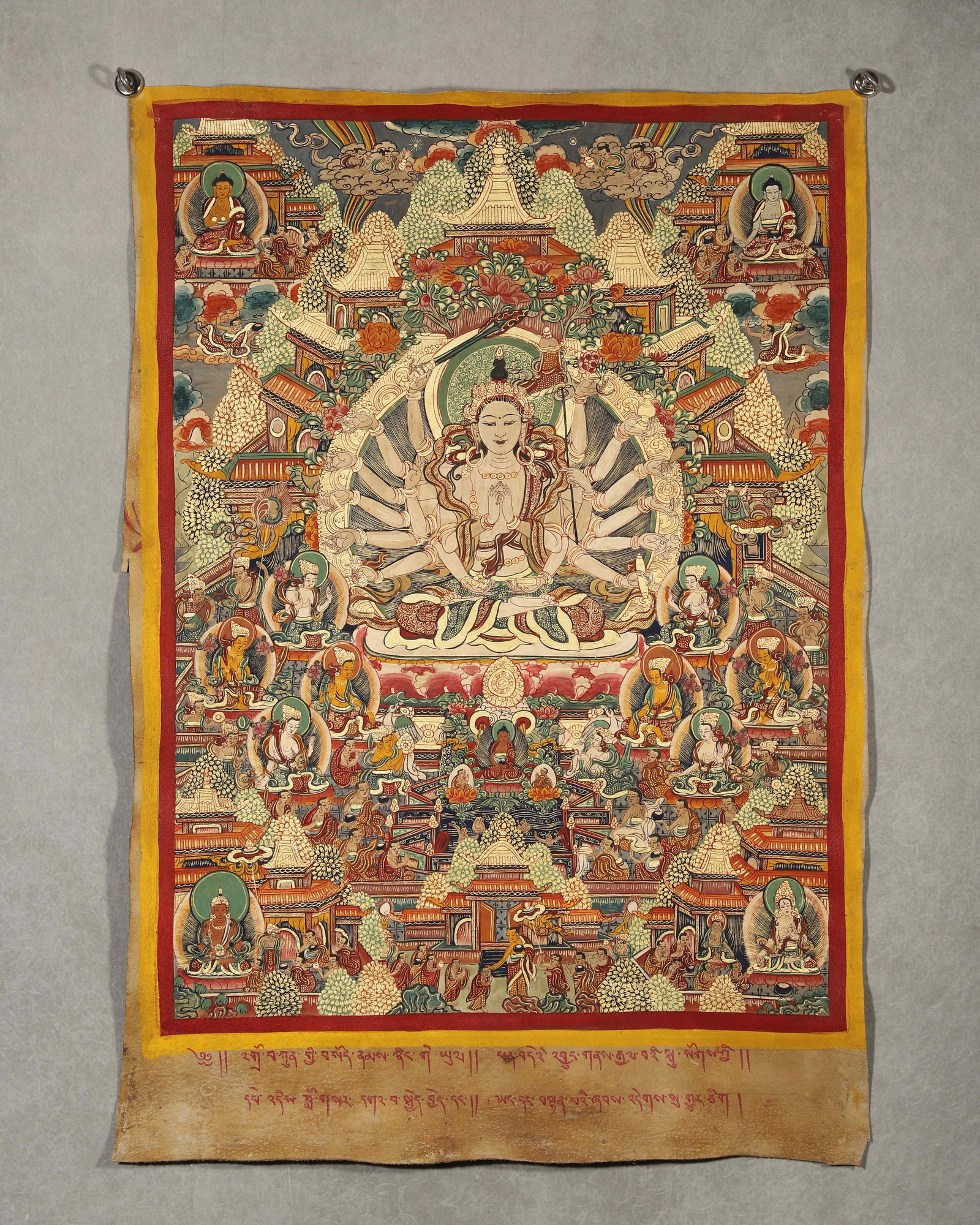 TIBETAN BUDDHIST THANGKA OF THOUSAND-ARMED AVALOKITESHVARA WITH TIBETAN INSCRIPTIONS, 19TH CENTURY: 32.28in x 24.41in (82.0cm x 62.0cm)This 19th-century Tibetan Thangka depicts Thousand-Armed Avalokiteshvara in a pure land scene. Crafted with vivid mineral pigments and gilded details, it bears Tibet