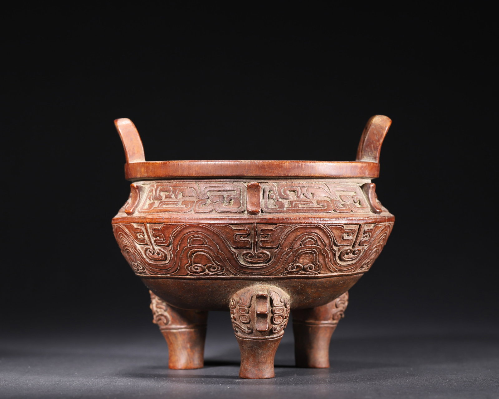 MID-QING DYNASTY, A BAMBOO CARVED TRIPOD DING CENSER IN ARCHAIC BRONZE STYLE: 6.69in x 5.91in (17.0cm x 15.0cm), 0.65lb (295.0g)This Mid-Qing bamboo tripod censer imitates Western Zhou bronze Ding. Carved with archaic interlocking scroll and scale patterns, it features beast-fa