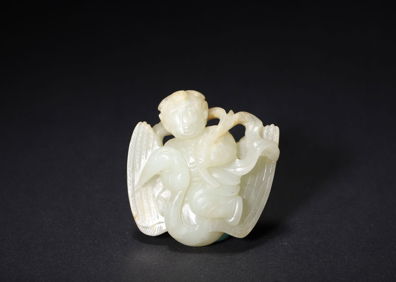 QING DYNASTY PALE GREEN JADE CARVED BOY ON CRANE PENDANT: 1.89in x 1.97in (4.8cm x 5.0cm) 0.110lbs (50g)A fine Qing Dynasty pale green jade pendant, carved with a serene boy seated on a crane, holding a sprig. The smooth texture, delicate details, and warm r