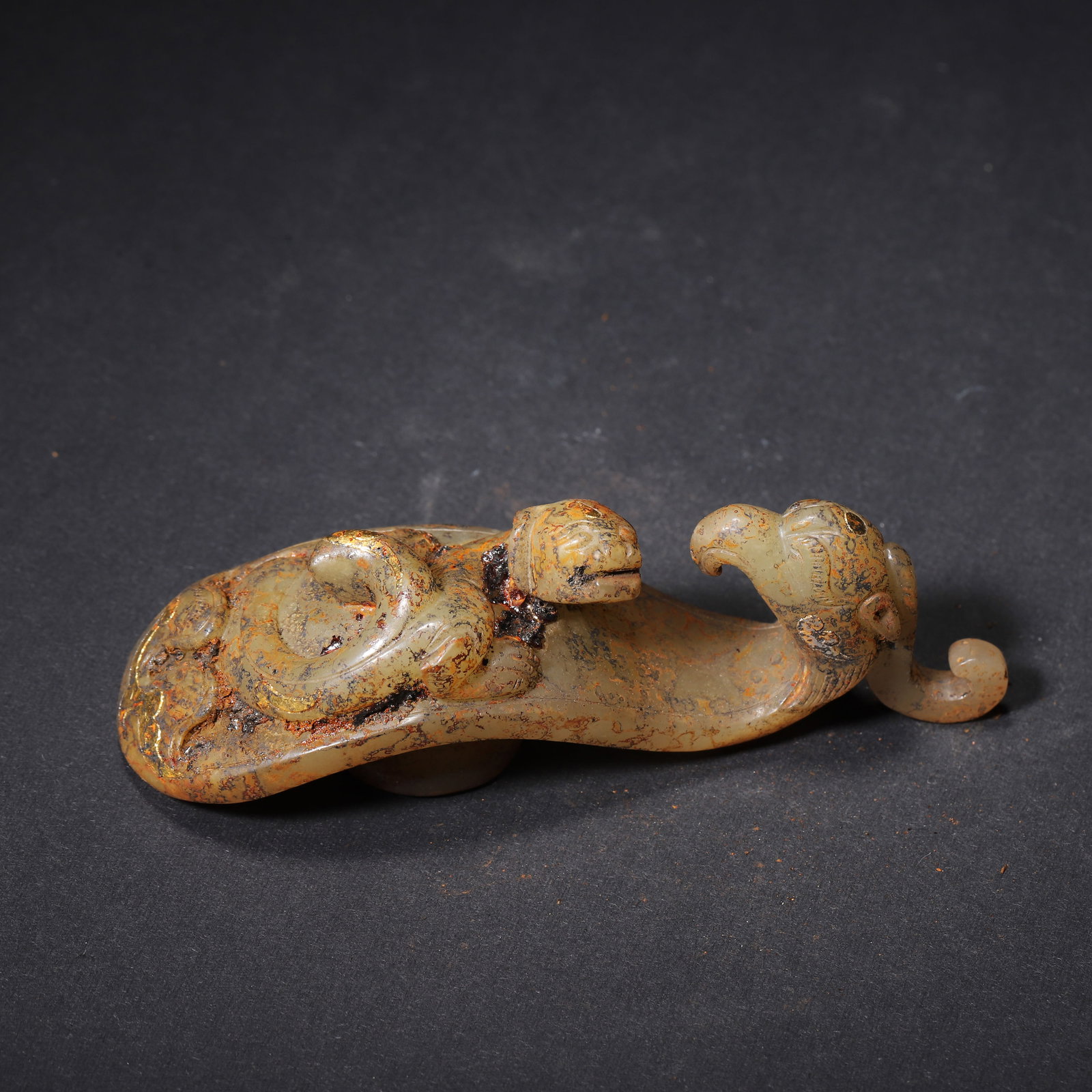 HAN DYNASTY GOLD-INLAID JADE GARMENT HOOK WITH PHOENIX HEAD AND CHI DRAGON: 3.66" x 1.18" x 1.18" (9.3cm x 3.0cm x 3.0cm) 0.146lb (66g)Carved from Hetian green jade, this Han Dynasty garment hook features a phoenix head and high-relief Chi dragon with gold inlay. Its circular