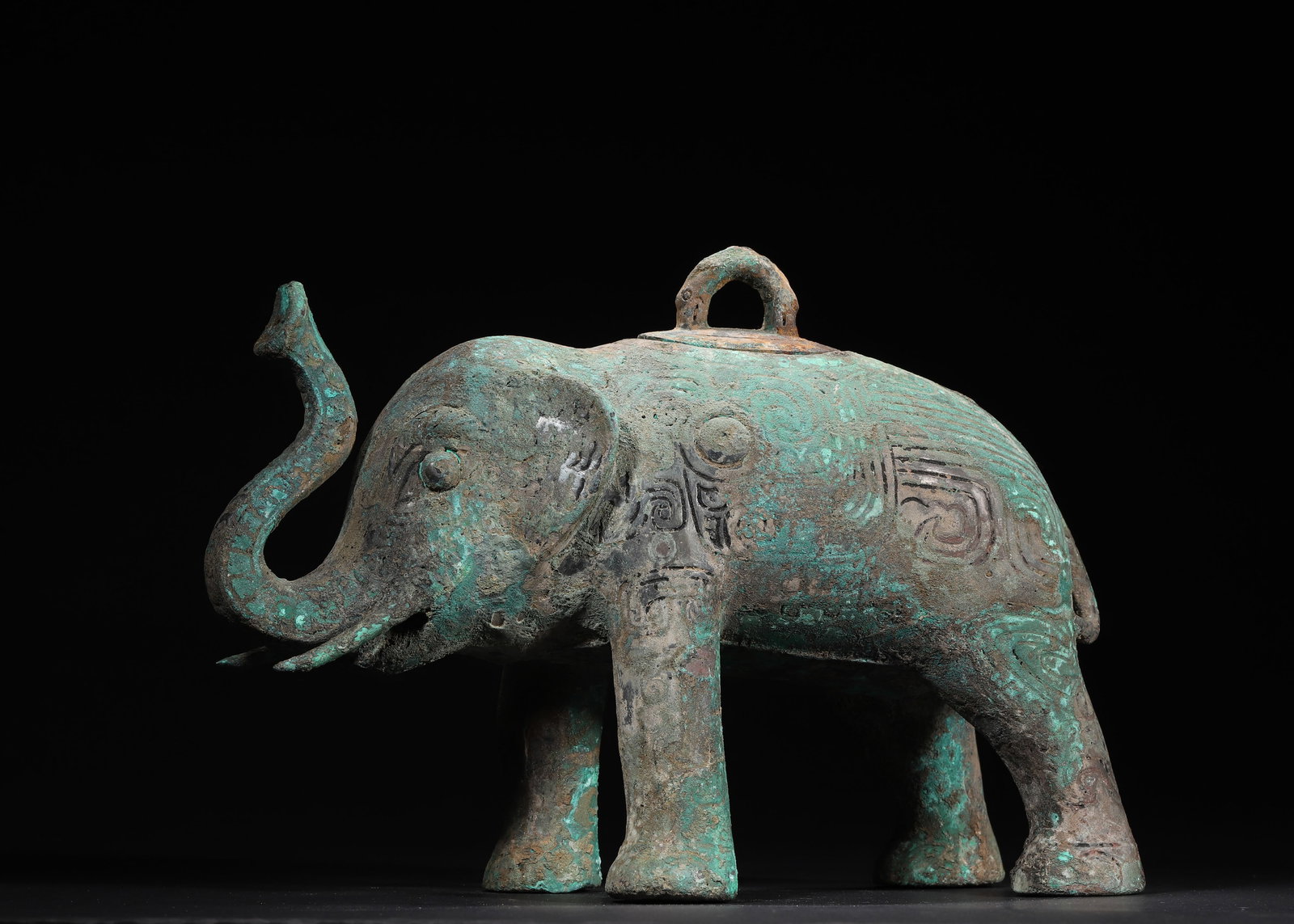 WESTERN ZHOU TO SPRING AND AUTUMN PERIOD BRONZE ELEPHANT-FORM ZUN VESSEL: 11.81in x 4.72in x 8.27in (30.0cm x 12.0cm x 21.0cm), 10.08lb (4572.0g)A fine Western Zhou to Spring and Autumn bronze elephant-form zun vessel, with a removable lid on its back, densely decorated wit
