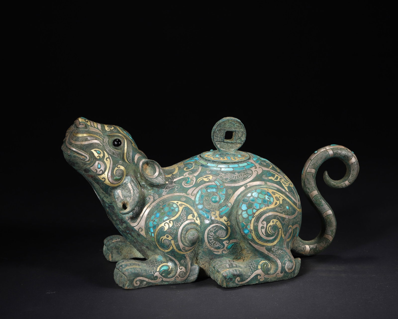 A FINE HAN DYNASTY BRONZE VESSEL WITH GOLD, SILVER AND TURQUOISE INLAY IN THE FORM OF A RAT: 10.24in x 5.51in x 5.51in (26.0cm x 14.0cm x 14.0cm), 4.422lb (2006.0g)This Han Dynasty bronze vessel, shaped as an auspicious rat, is adorned with intricate gold, silver inlay and turquoise. The coin