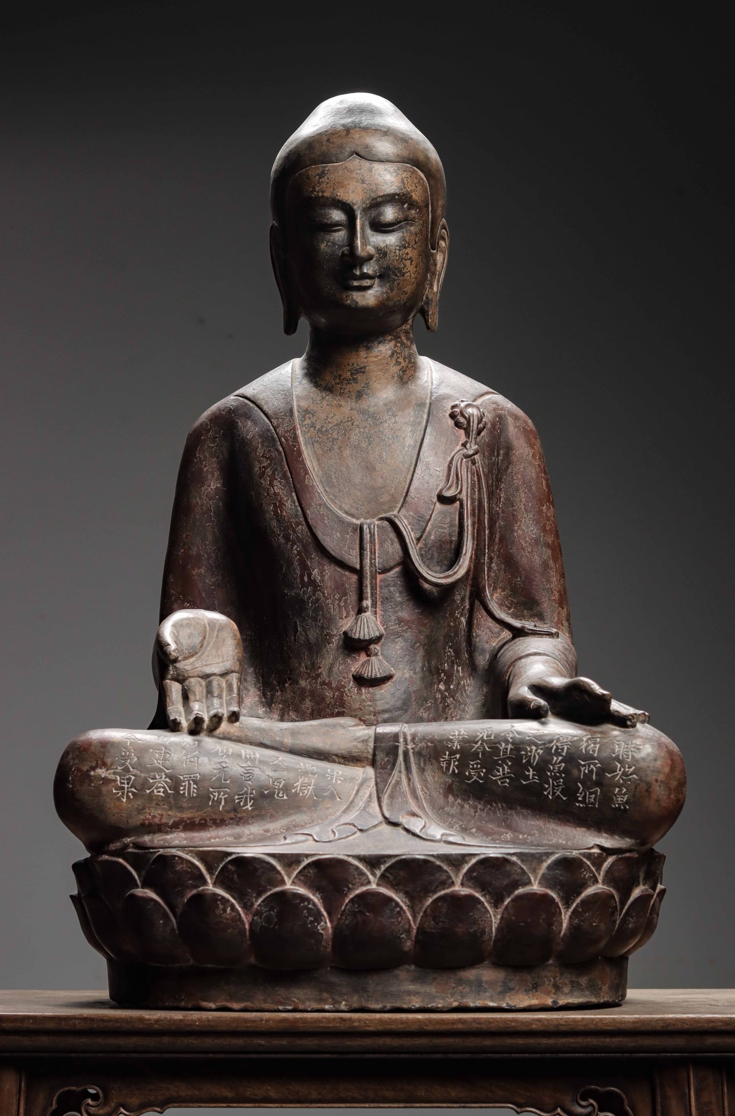MING DYNASTY, BLACK BLUESTONE PAINTED SAKYAMUNI BUDDHA SEATED STATUE WITH INSCRIPTIONS: 30.71" x 18.9" x 15.75" (78cm x 48cm x 40cm)A fine Ming Dynasty black bluestone painted Sakyamuni Buddha statue, serene face, elaborate robe carvings, seated on lotus pedestal, with inscriptions on le