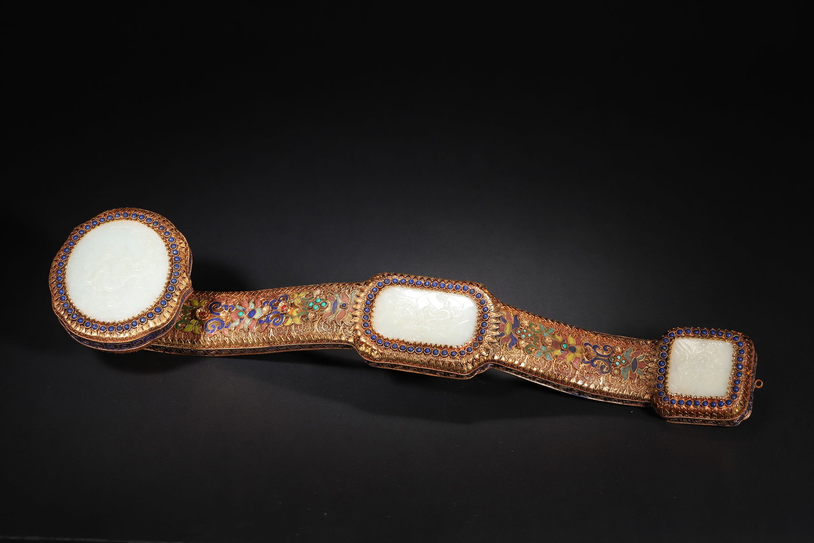 A FINE IMPERIAL GILT-SILVER FILIGREE AND ENAMEL RUYI SCEPTRE WITH INLAID WHITE JADE DRAGON PANELS,: 19.69in x 4.33in (50.0cm x 11.0cm), 4.78lb (2168.0g)This imperial ruyi sceptre, crafted in the Qianlong period, features gilt-silver filigree, enamel, lapis lazuli and turquoise inlays, with three whi