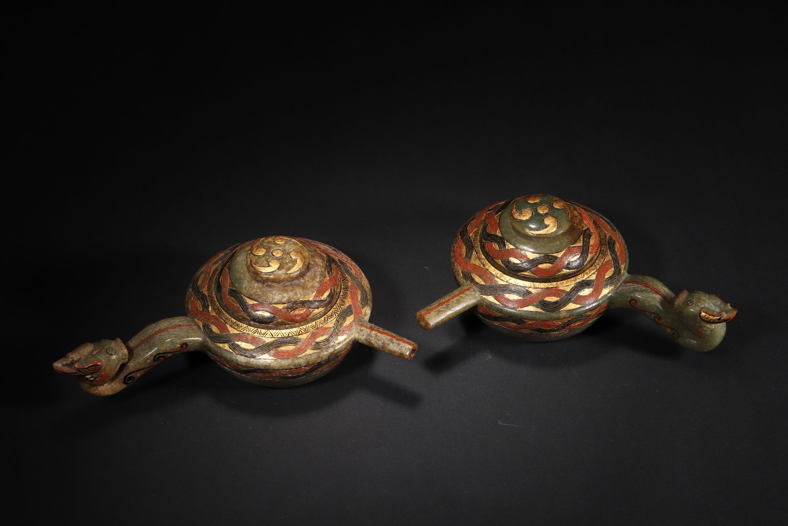A FINE PAIR OF HAN DYNASTY GREEN JADE EWERS WITH GOLD-INLAID AND PAINTED DRAGON-HEAD HANDLES: 6.3in x 5.12in x 2.76in (16.0cm x 13.0cm x 7.0cm), 1.431lb (649.0g)This pair of Han Dynasty green jade ewers features intricate gold-inlaid interlocking patterns and painted dragon-head handles. The h