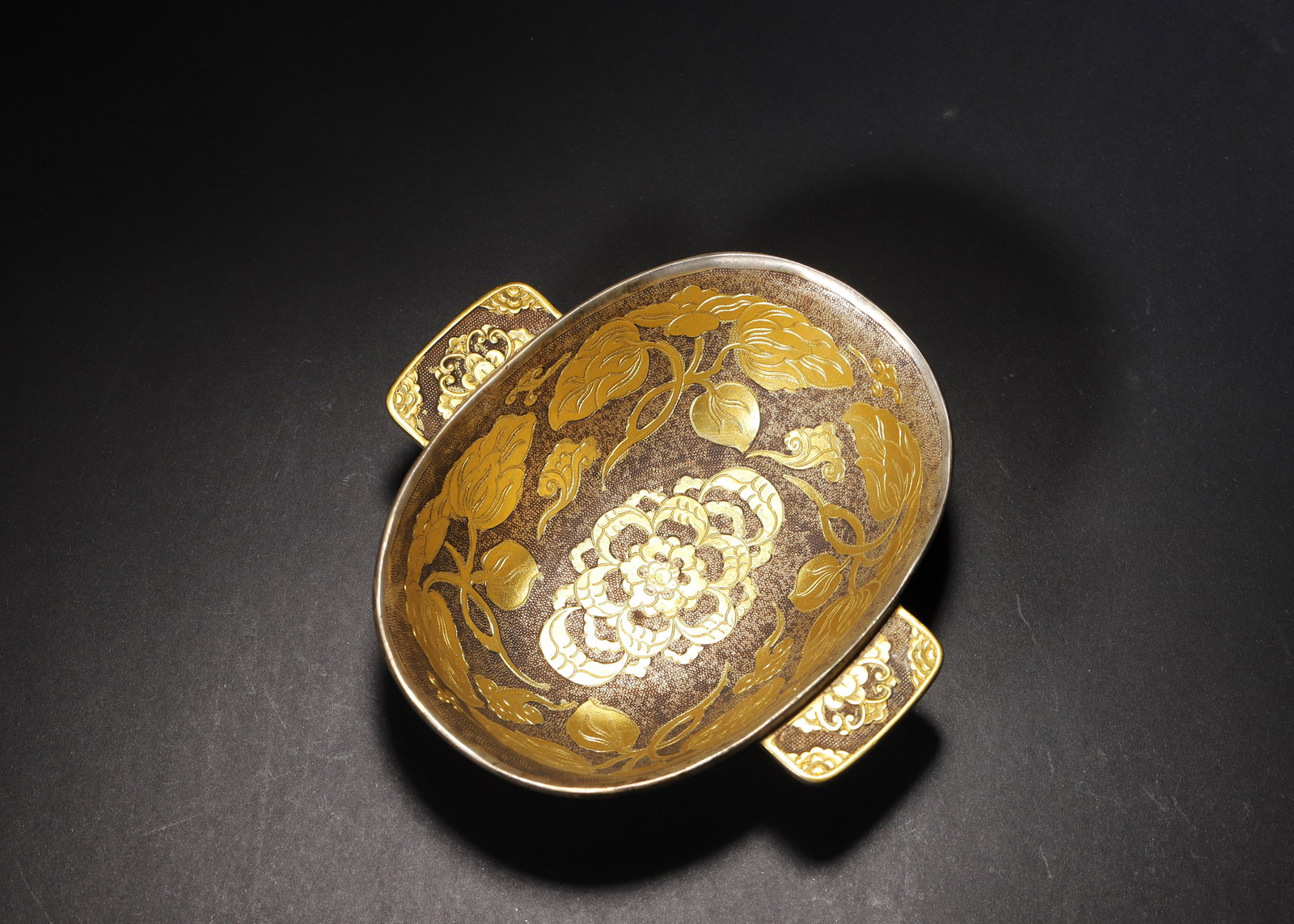 A FINE TANG DYNASTY GILT-SILVER 'YU SHANG' CUP WITH BIRD AND FLOWER MOTIFS: 5.31in x 5.12in x 1.57in (13.5cm x 13.0cm x 4.0cm), 0.699lb (317.0g)This Tang Dynasty 'Yu Shang' cup is crafted from gilt-silver, featuring intricate bird-and-flower motifs against a fish-roe ground. 