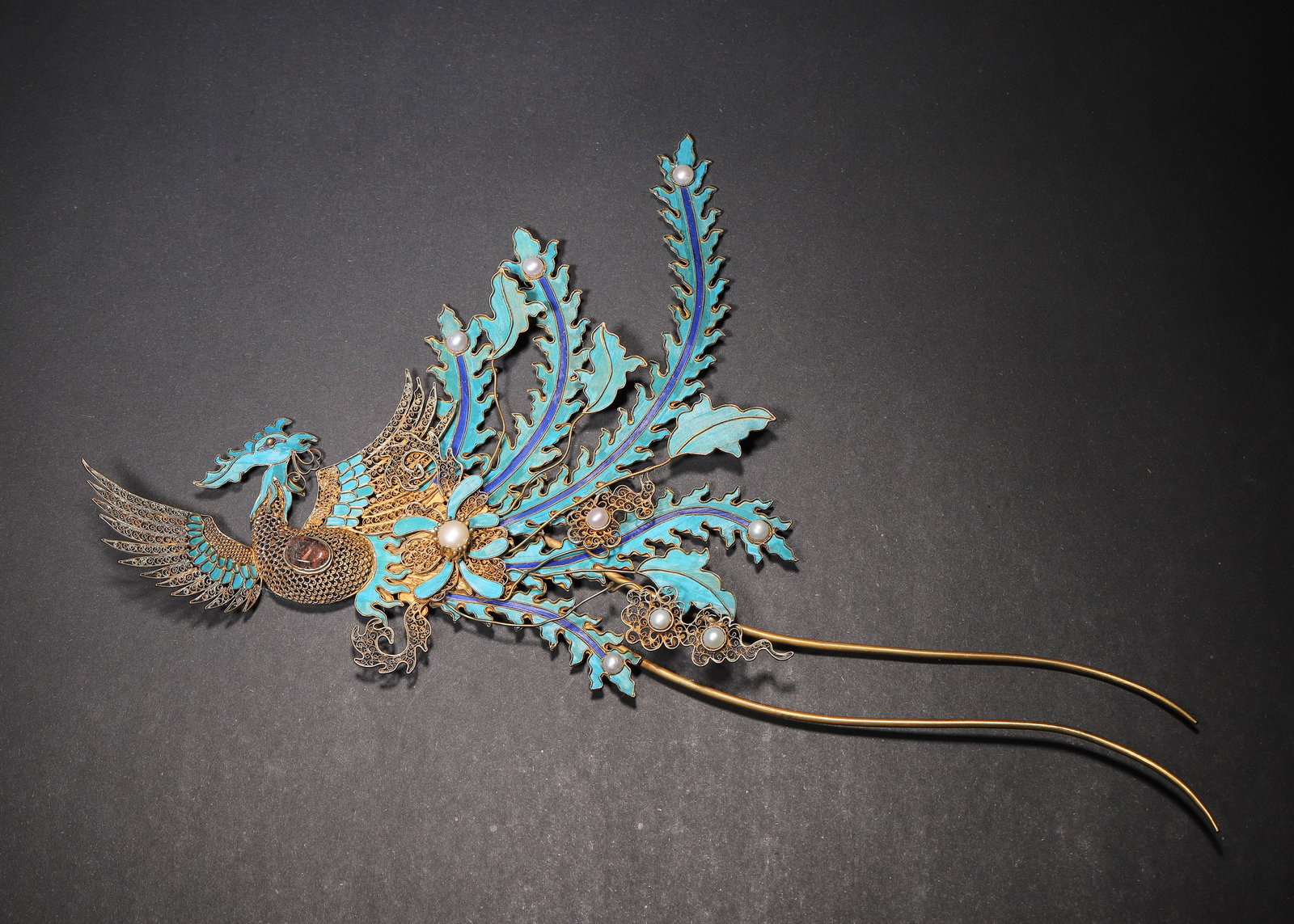 A FINE QING DYNASTY GILT-SILVER FILIGREE AND KINGFISHER FEATHER PHOENIX HAIRPIN WITH GEM INLAY: 10.24in x 5.91in (26.0cm x 15.0cm), 0.117lb (53.0g)This Qing Dynasty phoenix hairpin is crafted from gilt-silver filigree with vibrant kingfisher feather inlay, featuring a dynamic phoenix motif and s