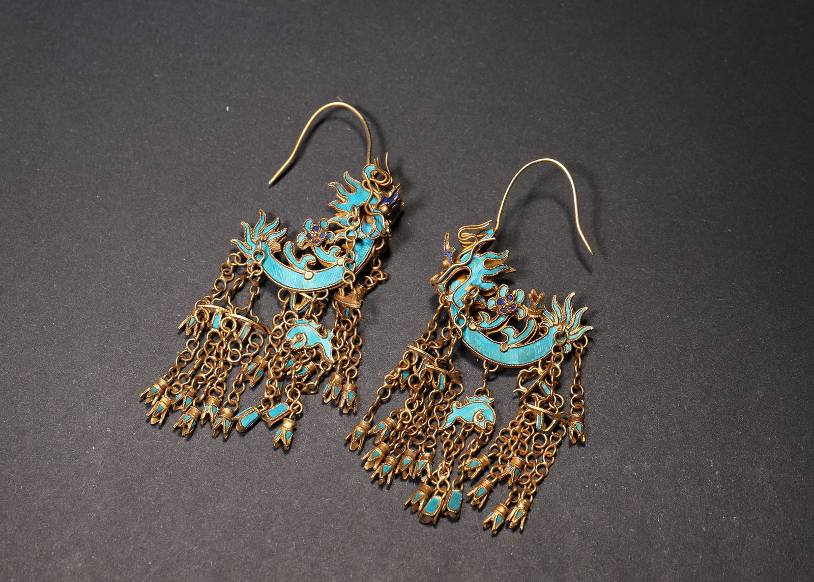 A FINE PAIR OF QING DYNASTY GILT-SILVER KINGFISHER FEATHER AND ENAMEL PHOENIX TASSEL EARRINGS: 2.76in x 1.18in (7.0cm x 3.0cm), 0.044lb (20.0g)This pair of Qing Dynasty earrings is crafted from gilt-silver with vibrant kingfisher feather and enamel phoenix motifs, adorned with delicate tassels.