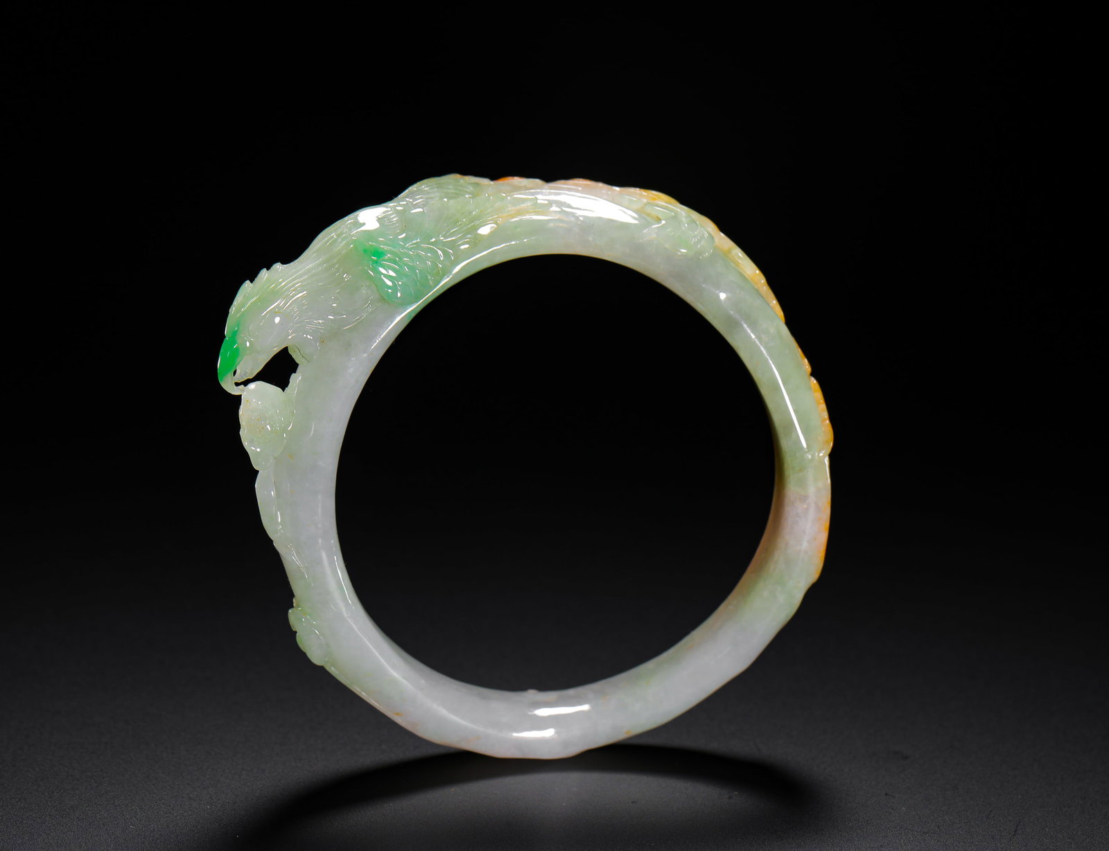 Jadeite Bracelet, Carved with Phoenix Amongst Peonies: Contemporary natural Jadeite with a unique three color swash of white, green and yellow, so-called Fu Lu Shou. The exquisite carving of a phoenix amongst peonies is striking and symbolizes wealth and 