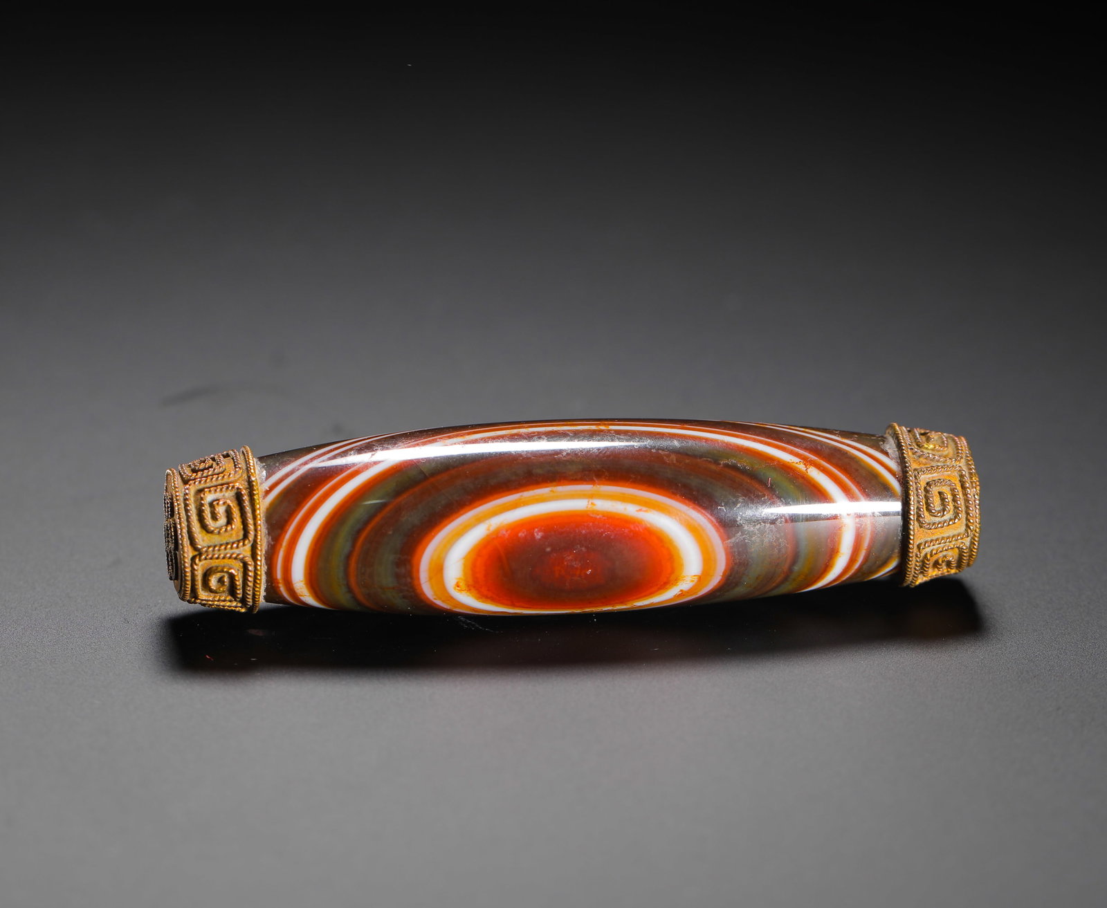 Natural Sky Eye Banded Agate with Gold Bead, Qing Dynasty: H:7.6cm(2.99in) D:2cm(0.79in) Weight:40g(0.09lb)This is a Qing Dynasty natural banded agate lezi. The main body is elongated, with distinct layered textures forming a natural "eye" pattern in red, whi