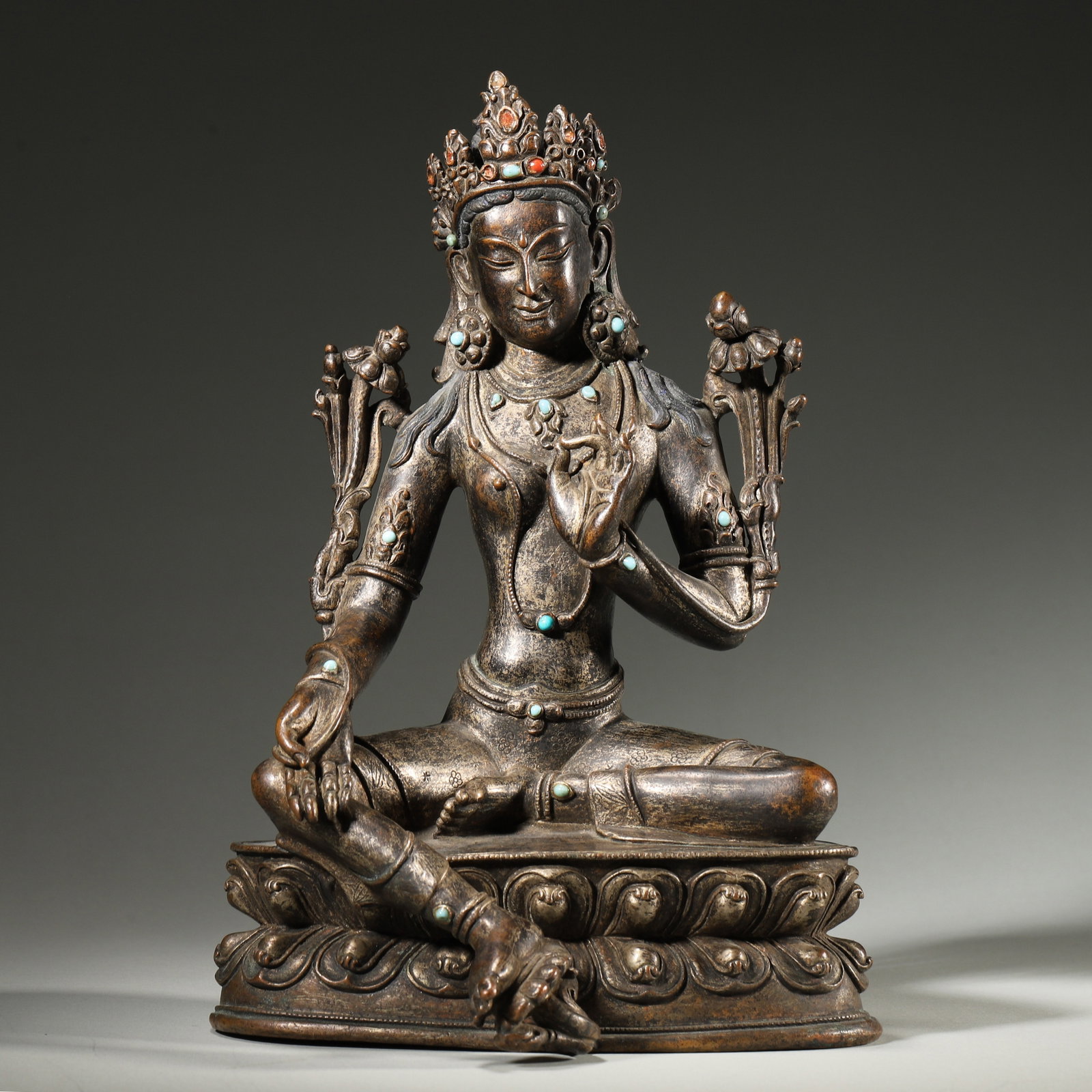 Bronze Green Tara, Turquoise and Coral Inlay, Qing Dynasty: A Qing dynasty Tibetan bronze figure of Green Tara, richly inlaid with natural turquoise and coral on the crown, necklaces, and bracelets. The deity is seated in relaxed lalitasana, with the right han