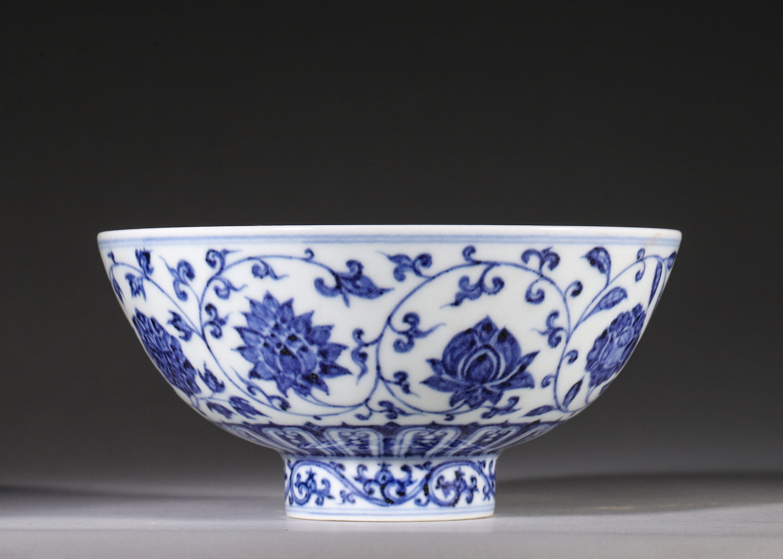 Blue and White Bowl with Interlocking Floral Scrolls, Xuande Period, Ming Dynasty: A blue and white bowl, Xuande period, Ming dynasty, painted with elegant interlocking four-season floral scrolls and a lotus band encircling the foot. The interior center bears a six-character Xuande 
