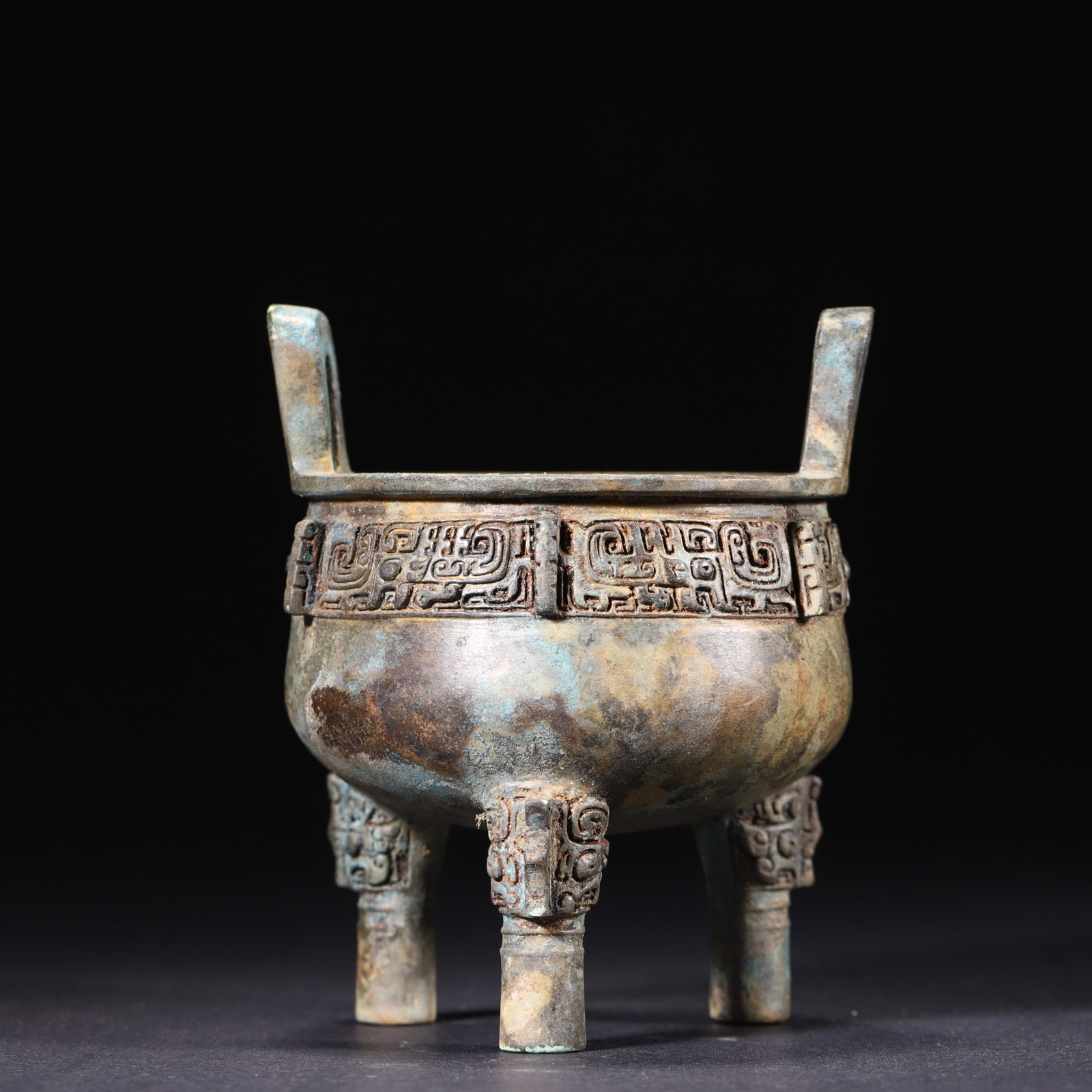 Western Zhou Dynasty Bronze Ritual Tripod Ding with Dragon Motifs: A Western Zhou dynasty bronze ritual ding with square upright handles, a rounded belly, and three legs decorated with beast-mask motifs. The rim is finely cast with symmetrical recumbent dragon patter
